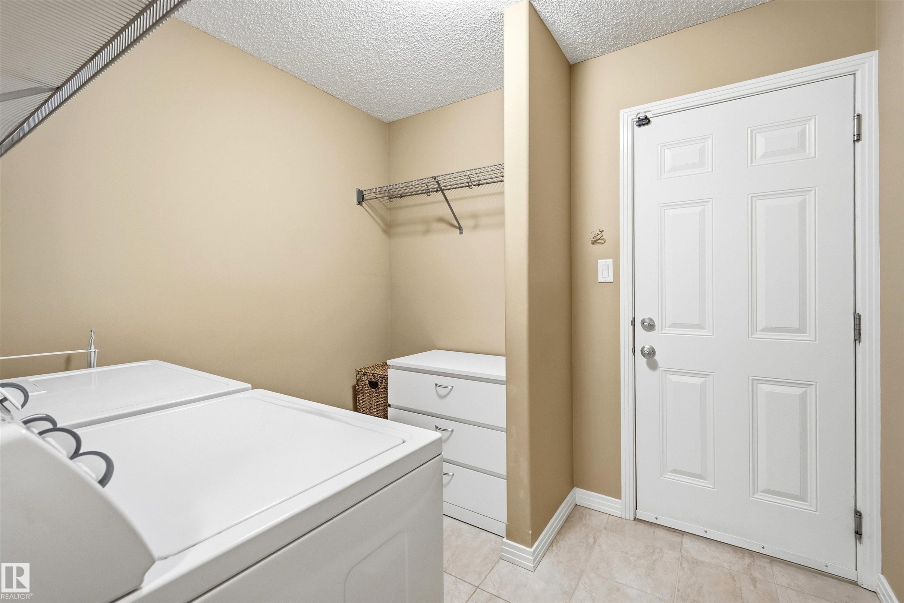 Utility area featuring light beige walls and a white paneled door - 2340 Hagen Link, Edmonton, AB - Indoor Photo Showing Laundry Room