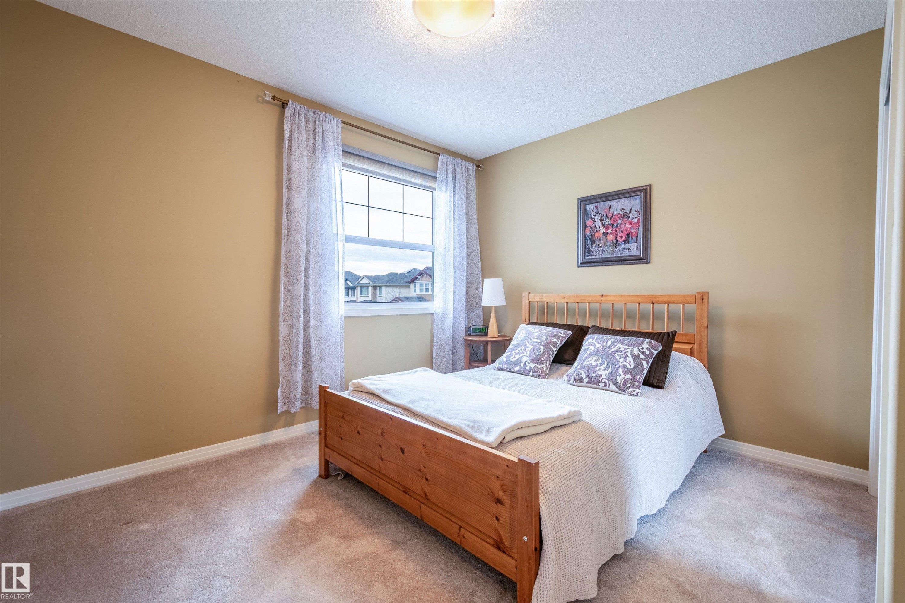 Bedroom featuring neutral wall paint, carpeted flooring, a window with grid patterns, and a built-in overhead light fixture - 2340 Hagen Link, Edmonton, AB - Indoor Photo Showing Bedroom