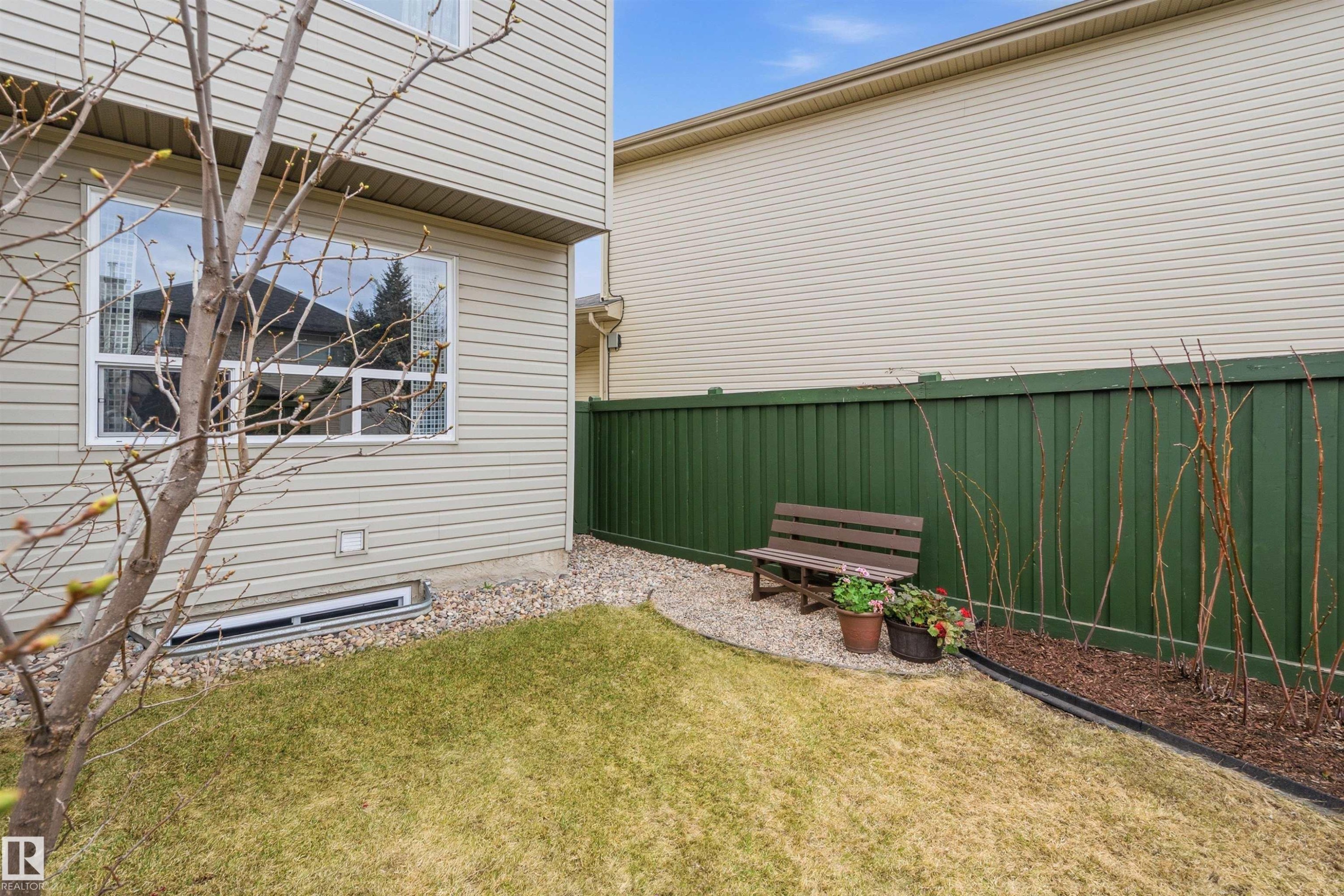Private backyard space featuring a green privacy fence, a manicured lawn, and a gravel accent area - 2340 Hagen Link, Edmonton, AB - Outdoor