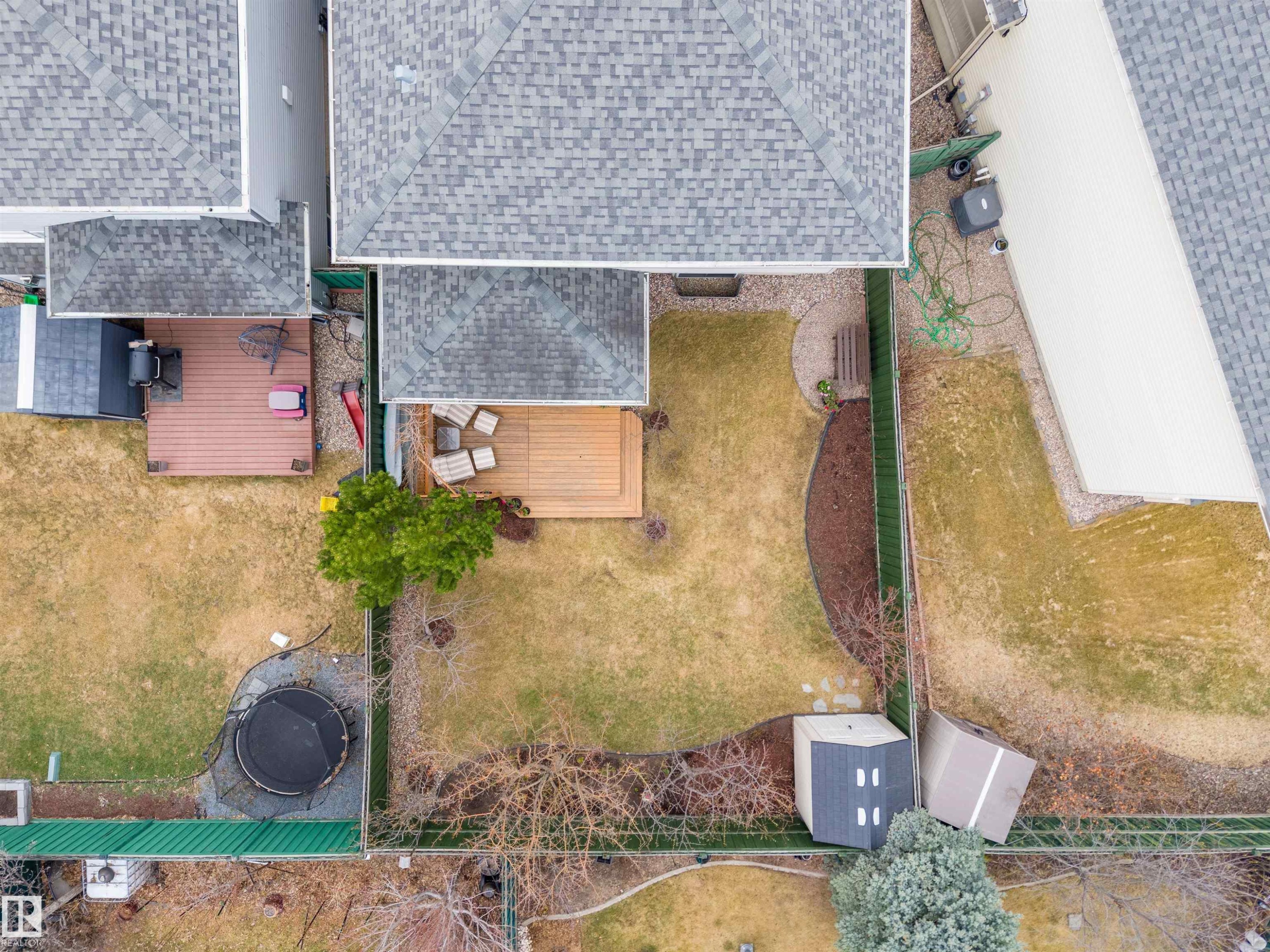 Expansive backyard featuring a large central lawn area, a wood-finish deck with seating, and a privacy fence - 2340 Hagen Link, Edmonton, AB - Outdoor