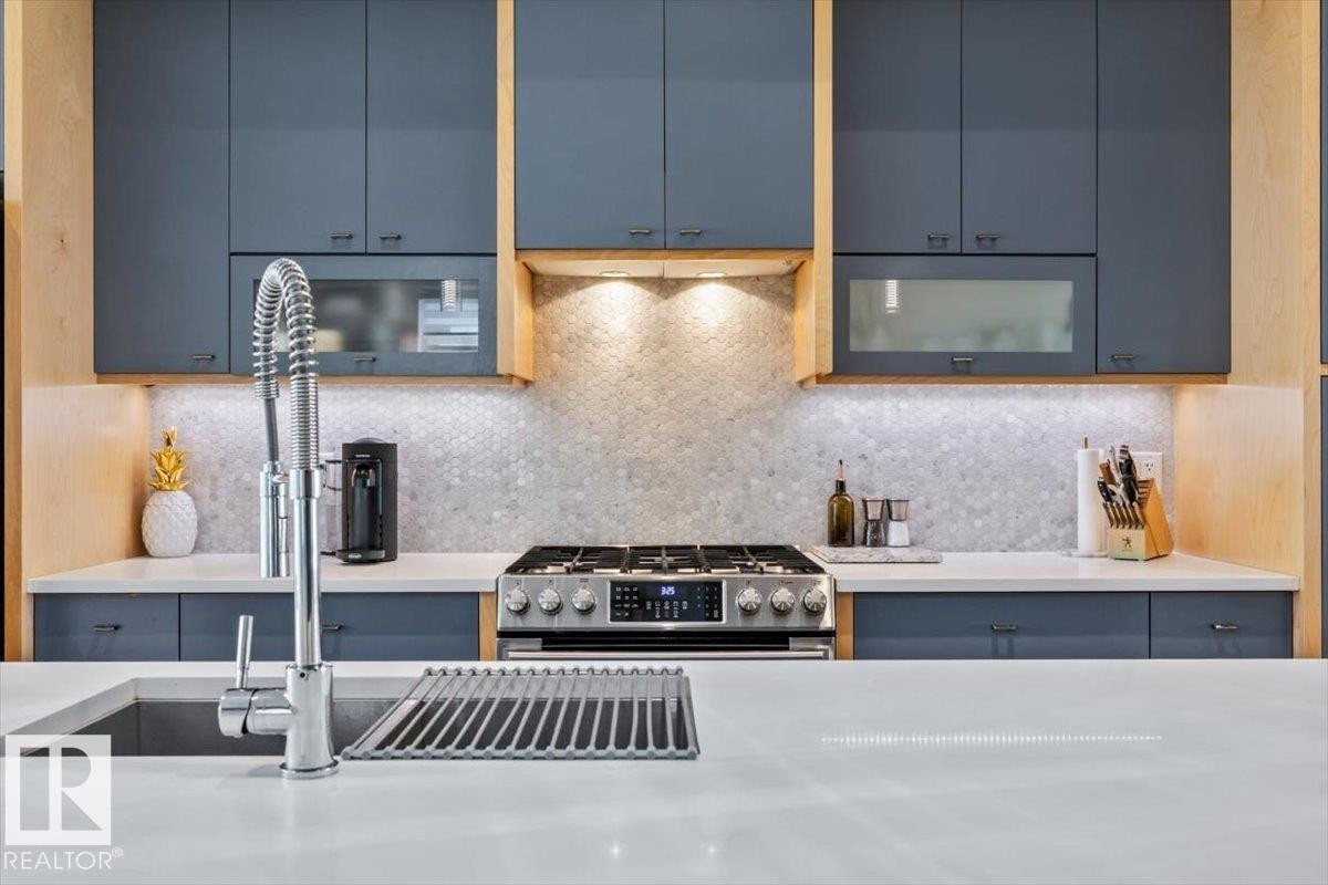 Modern kitchen showcasing rich blue cabinetry with wood-finish accents - 11245 64 Street, Edmonton, AB - Indoor Photo Showing Kitchen With Double Sink With Upgraded Kitchen