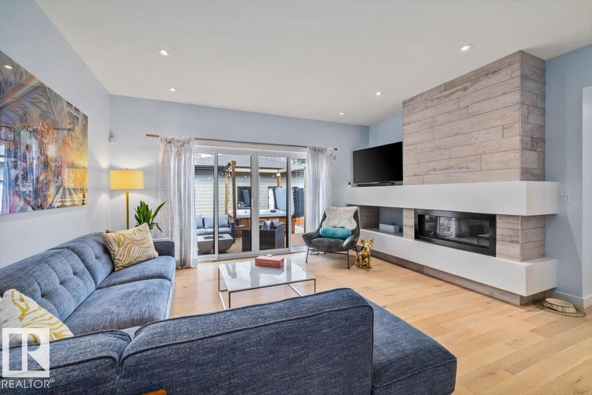 Living area featuring wood-finish flooring, recessed lighting, and a modern fireplace with a tiled surround - 11245 64 Street, Edmonton, AB - Indoor Photo Showing Living Room With Fireplace