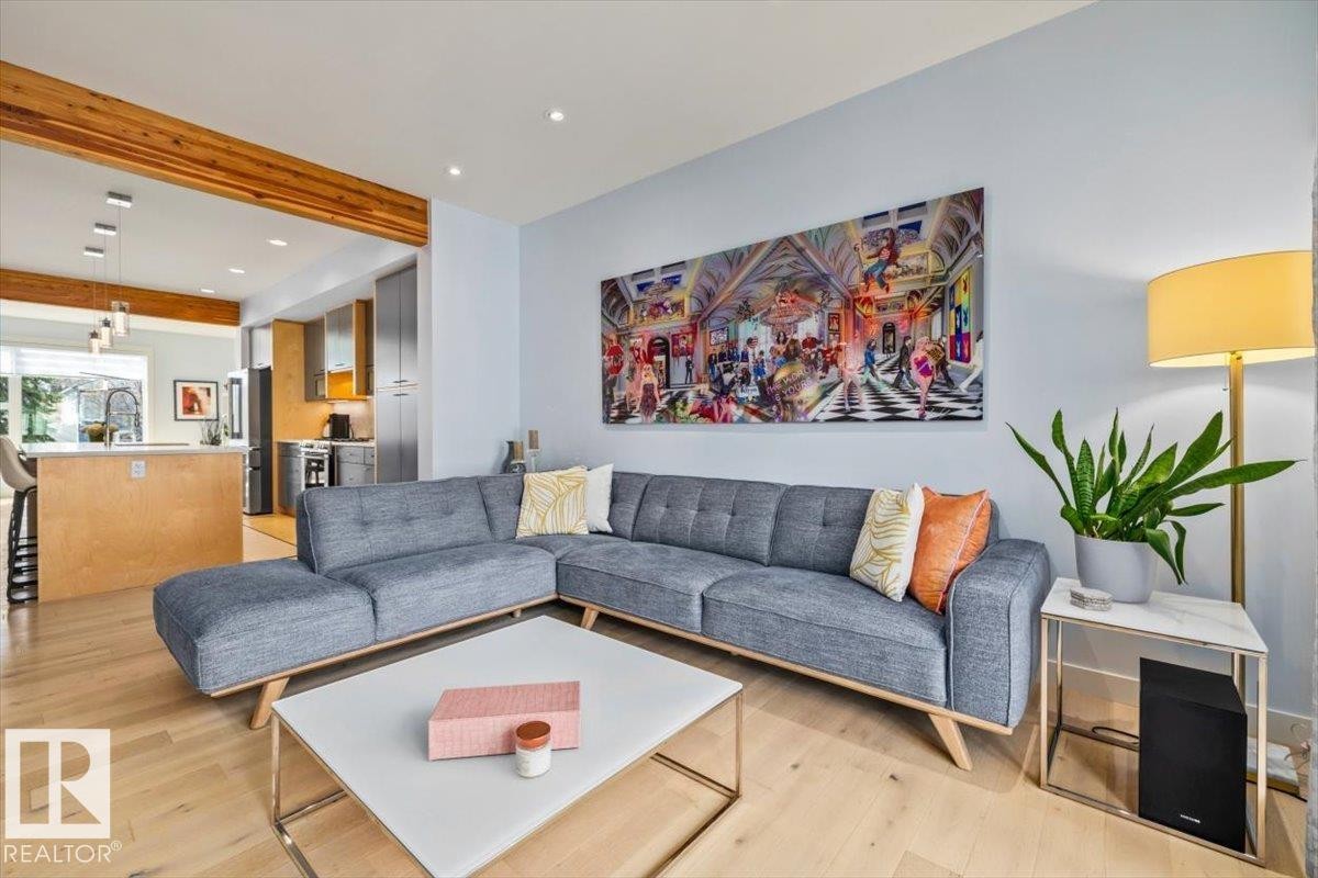 Open-concept living area featuring light wood-finish flooring, recessed lighting, and a prominent wood beam detail - 11245 64 Street, Edmonton, AB - Indoor Photo Showing Living Room