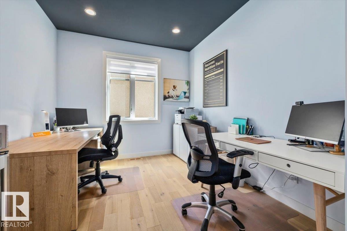 Dedicated workspace featuring light wood-finish flooring, a window with roller blinds, recessed ceiling lighting, and a dark contrasting ceiling - 11245 64 Street, Edmonton, AB - Indoor Photo Showing Office