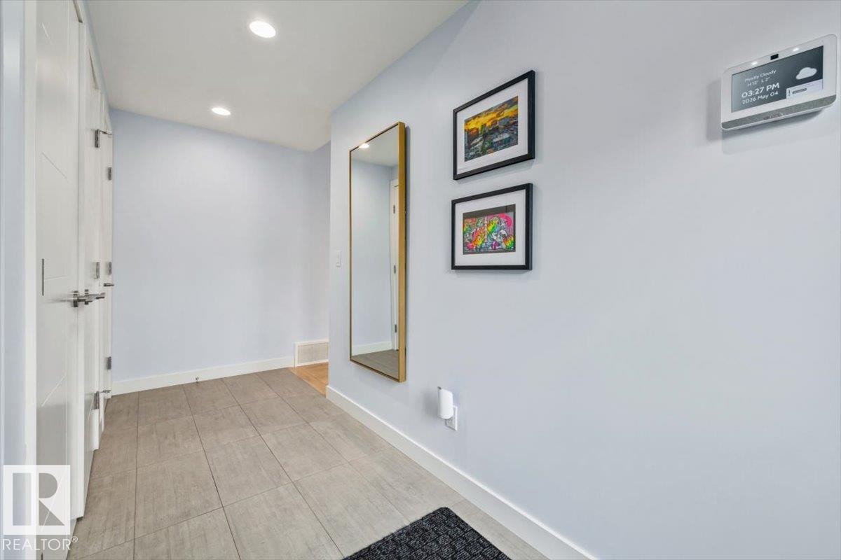 Recessed ceiling lighting illuminates the entry hall featuring modern doors and a full-length mirror - 11245 64 Street, Edmonton, AB - Indoor Photo Showing Other Room