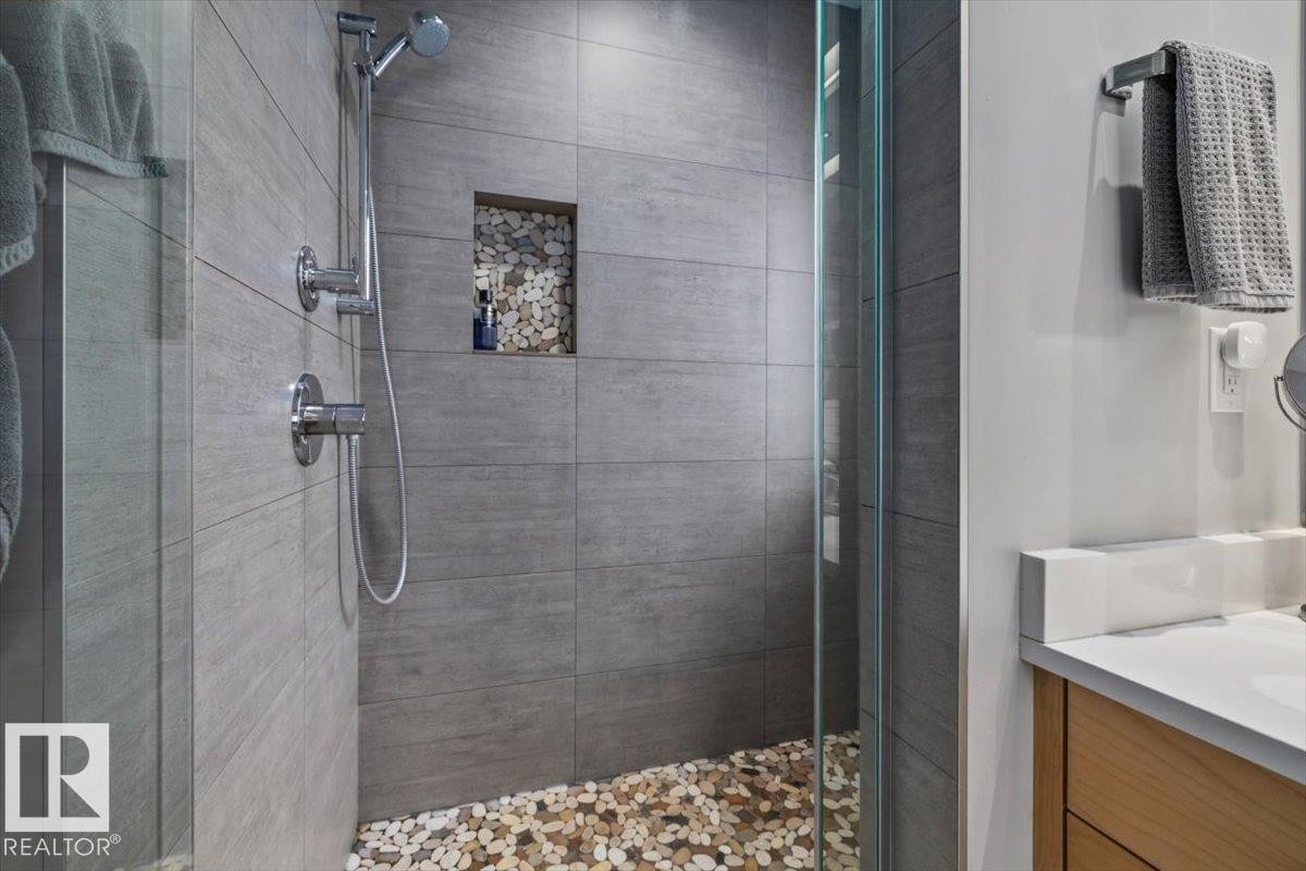 Walk-in shower with clear glass enclosure and pebble floor - 11245 64 Street, Edmonton, AB - Indoor Photo Showing Bathroom