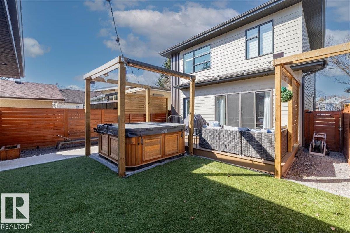 Private backyard featuring a built-in hot tub with a wooden surround, artificial turf, and a composite deck - 11245 64 Street, Edmonton, AB - Outdoor