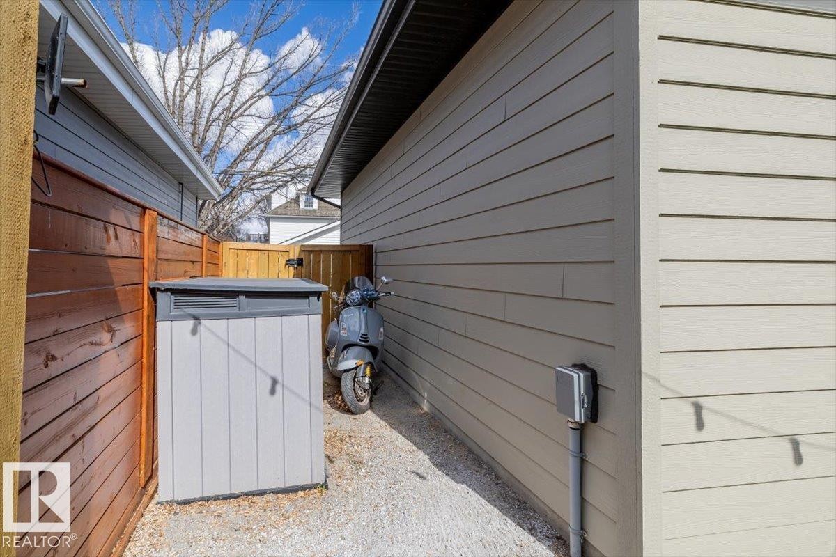 Gravel pathway featuring a privacy fence, a built-in storage unit, and exterior siding - 11245 64 Street, Edmonton, AB - Outdoor With Exterior