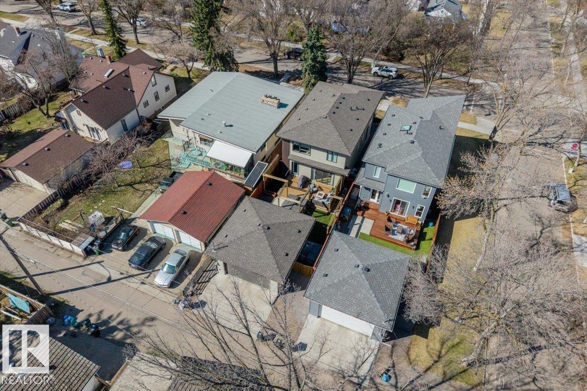 Aerial view showcasing multiple residential properties, featuring a grey-sided home with a dark-grey shingle roof, rear deck, and a fenced yard with artificial turf - 11245 64 Street, Edmonton, AB - Outdoor With View
