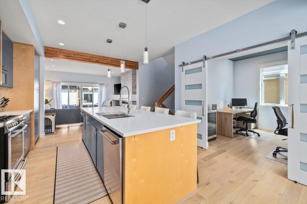 Open-concept kitchen featuring a large island with white countertops, stainless steel appliances, and pendant lighting - 11245 64 Street, Edmonton, AB - Indoor Photo Showing Kitchen With Upgraded Kitchen