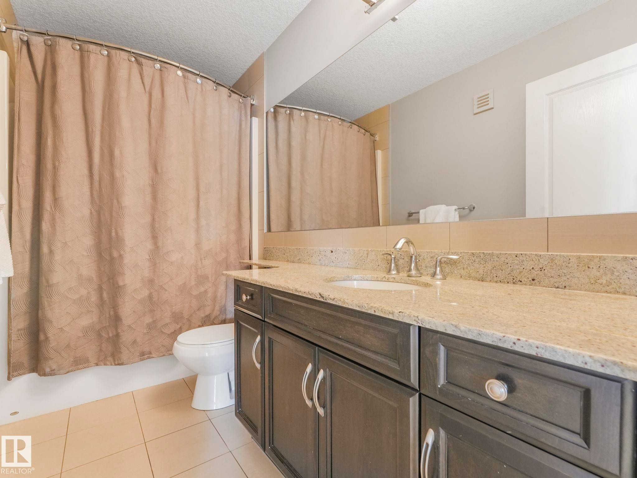 Bathroom featuring a vanity with a light-toned countertop, integrated sink, and chrome fixtures - 932 Summerside Link, Edmonton, AB - Indoor Photo Showing Bathroom
