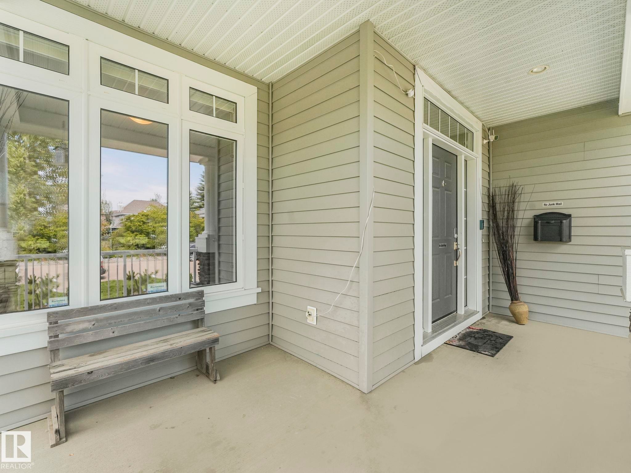 Covered front porch featuring light gray horizontal siding and a dark gray entry door - 932 Summerside Link, Edmonton, AB - Outdoor With Exterior