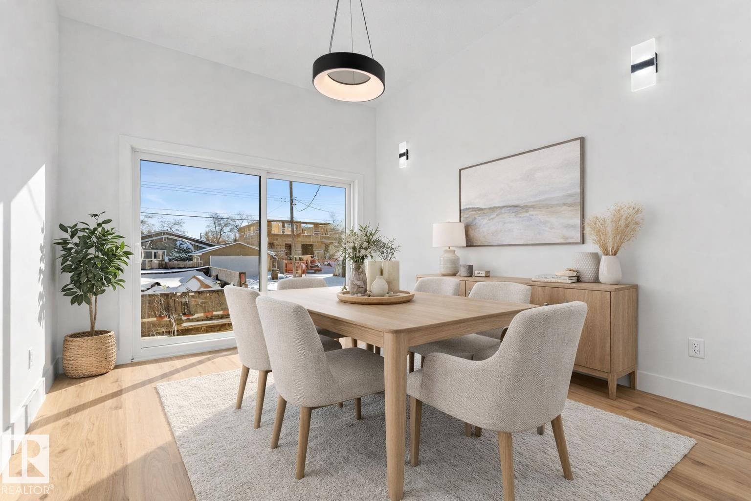 Bright dining area featuring hardwood flooring, white walls, and a contemporary light fixture - 11019 132 St, Edmonton, AB - Indoor Photo Showing Dining Room