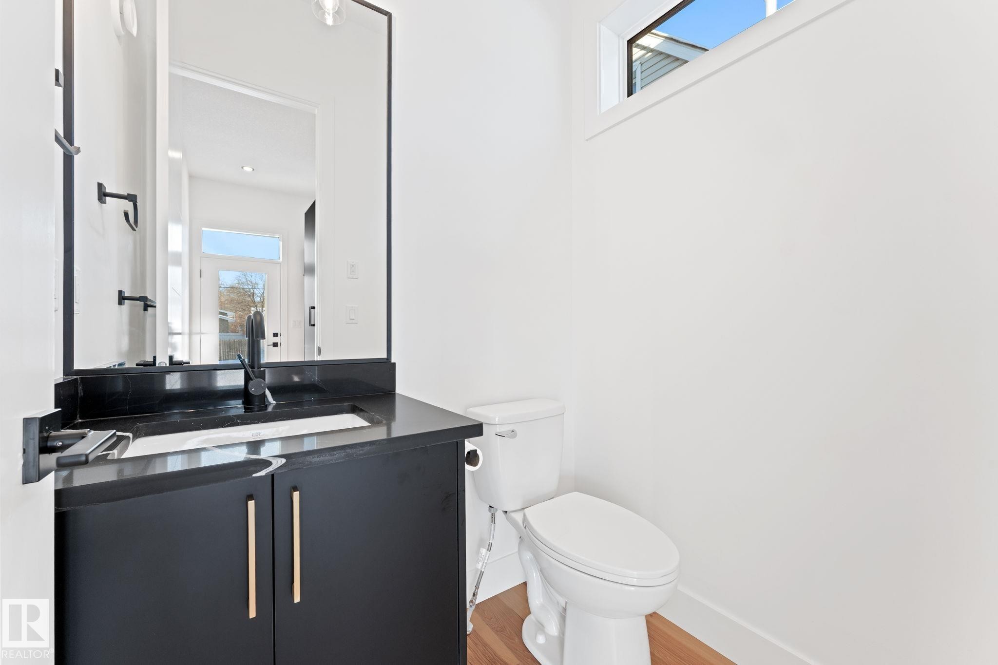 Well-appointed bathroom featuring a dark vanity with gold hardware, a black countertop, and a contemporary black faucet - 11019 132 St, Edmonton, AB - Indoor Photo Showing Bathroom