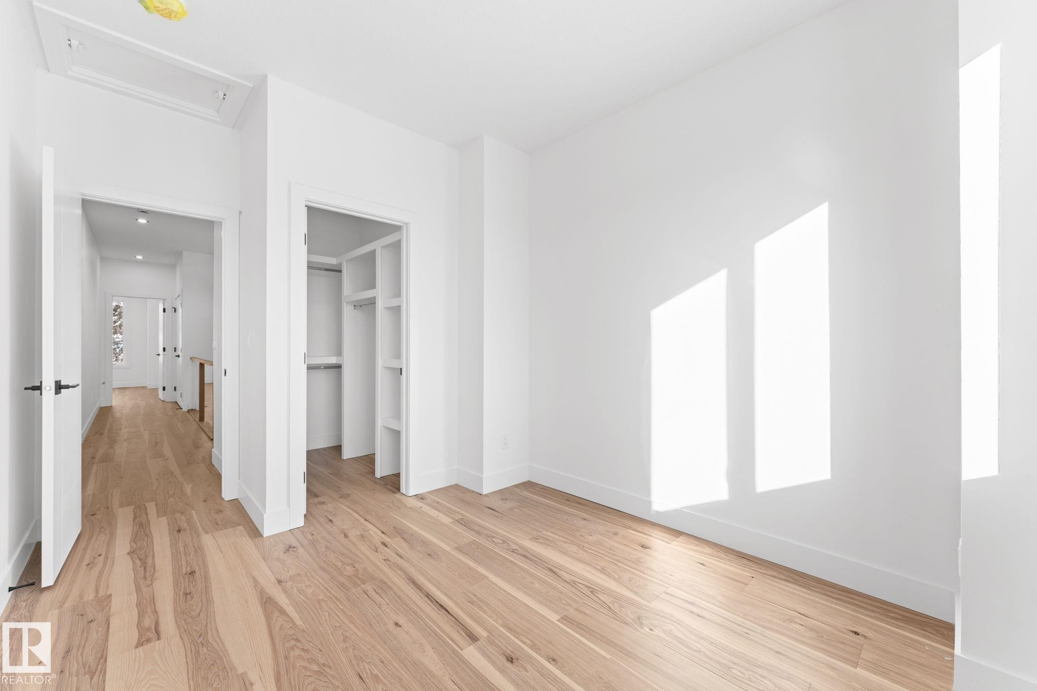This room features hardwood floors, white walls, and a built-in closet with shelving and a hanging rod - 11019 132 St, Edmonton, AB - Indoor Photo Showing Other Room