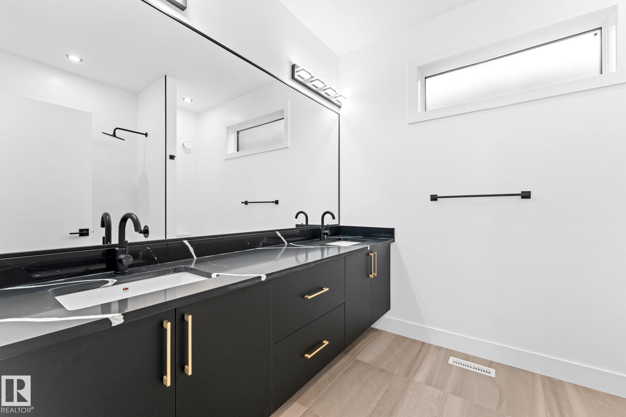 Spacious vanity with two sinks, dark cabinetry, and gold-toned hardware, complemented by a large mirror and recessed lighting - 11019 132 St, Edmonton, AB - Indoor Photo Showing Bathroom