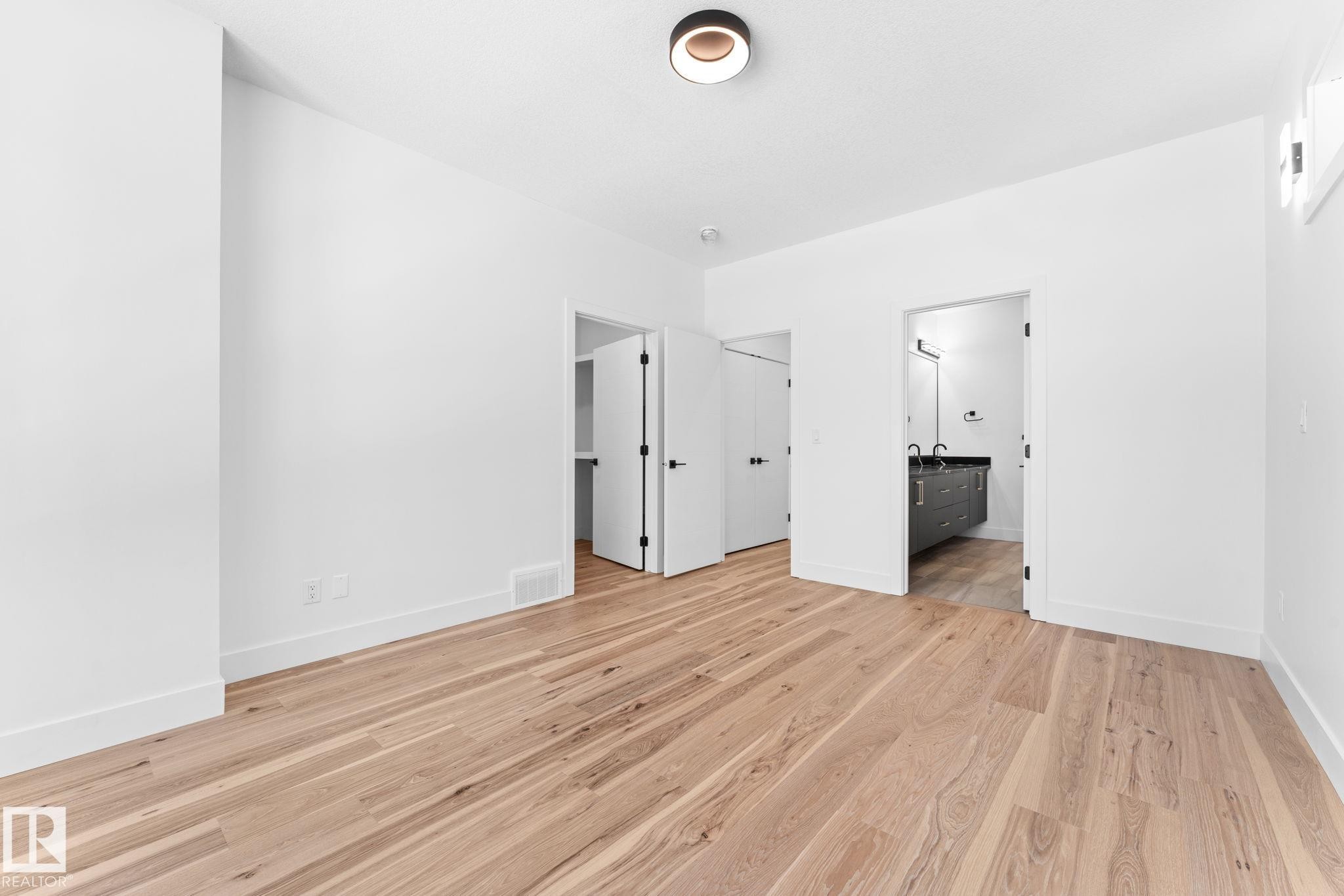 This room features light hardwood flooring, white walls, and a modern ceiling light fixture - 11019 132 St, Edmonton, AB - Indoor Photo Showing Other Room
