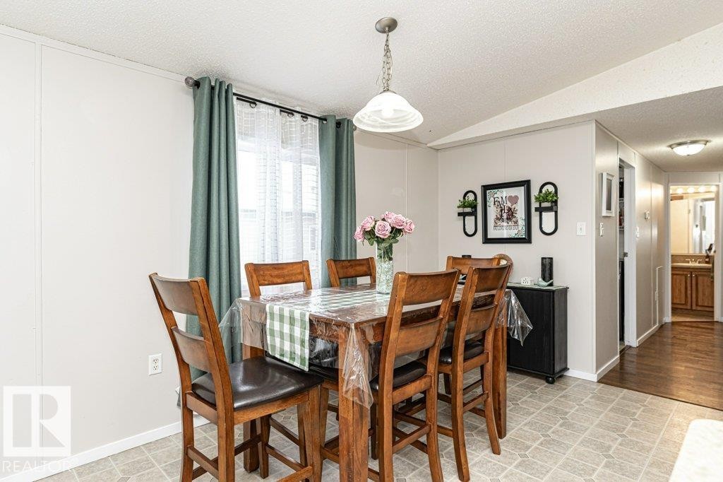 Dining area featuring a central chandelier, a window with curtains, and light-toned wall paneling - 1637 68 Avenue, Edmonton, AB - Indoor Photo Showing Dining Room