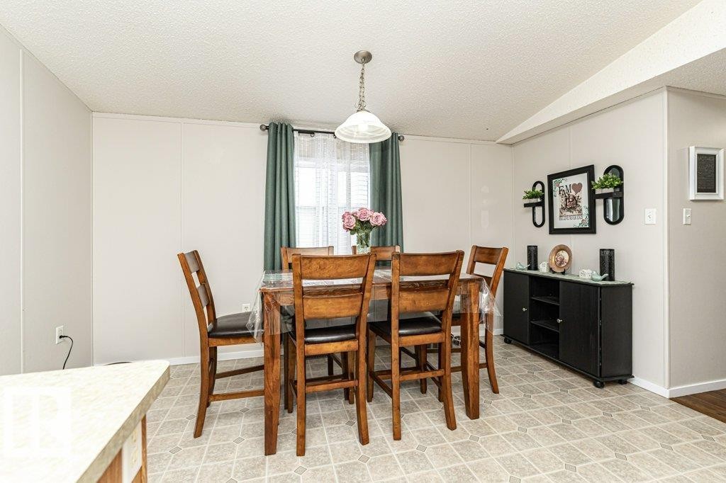 Dining area featuring wood-finish flooring, a window with sheer and solid curtains, a ceiling-mounted pendant light, and a built-in black storage cabinet - 1637 68 Avenue, Edmonton, AB - Indoor Photo Showing Dining Room