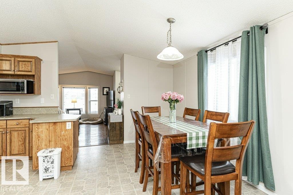 Dining area featuring a pendant light fixture, window with sheer and solid curtains, and wood-finish flooring - 1637 68 Avenue, Edmonton, AB - Indoor Photo Showing Dining Room