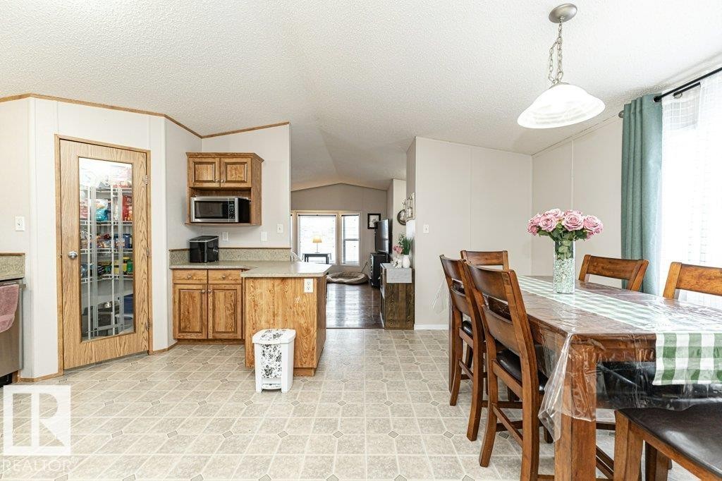 Kitchen and dining area featuring wood-finish cabinetry, a built-in microwave, and a glass-paneled pantry door - 1637 68 Avenue, Edmonton, AB - Indoor Photo Showing Dining Room