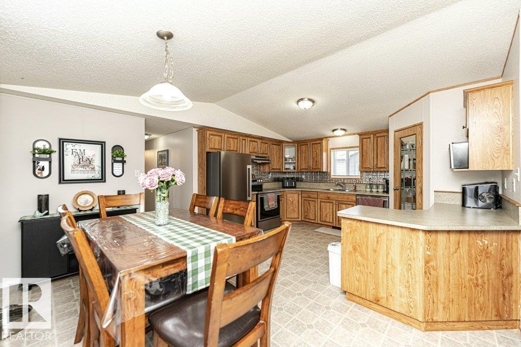 Open-concept kitchen and dining area featuring wood-finish cabinetry, a breakfast bar with laminate countertops, a tile backsplash, and built-in appliances - 1637 68 Avenue, Edmonton, AB - Indoor