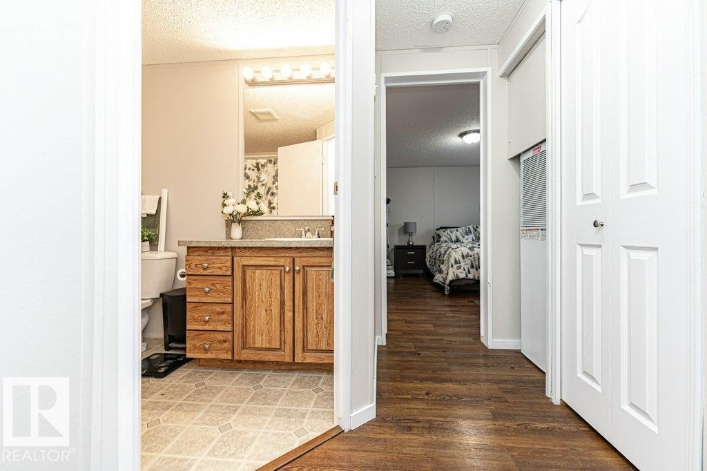 Bathroom vanity featuring wood-finish cabinetry, a light-toned countertop, and a mirrored medicine cabinet - 1637 68 Avenue, Edmonton, AB - Indoor Photo Showing Other Room