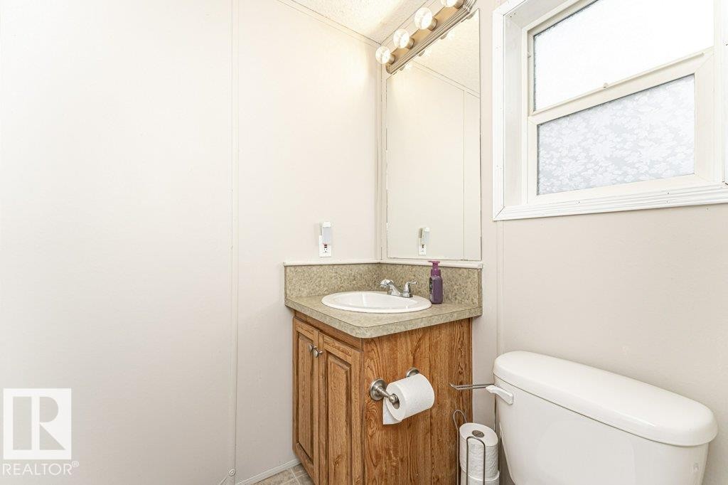 Corner vanity with wood-finish cabinetry and a speckled countertop - 1637 68 Avenue, Edmonton, AB - Indoor Photo Showing Bathroom
