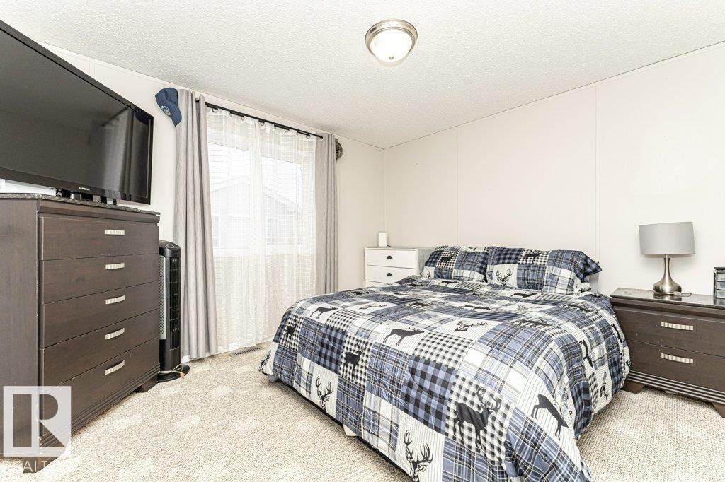 Bedroom featuring light-toned carpeting, a window with vertical blinds and curtains, and a flush-mount ceiling light fixture - 1637 68 Avenue, Edmonton, AB - Indoor Photo Showing Bedroom