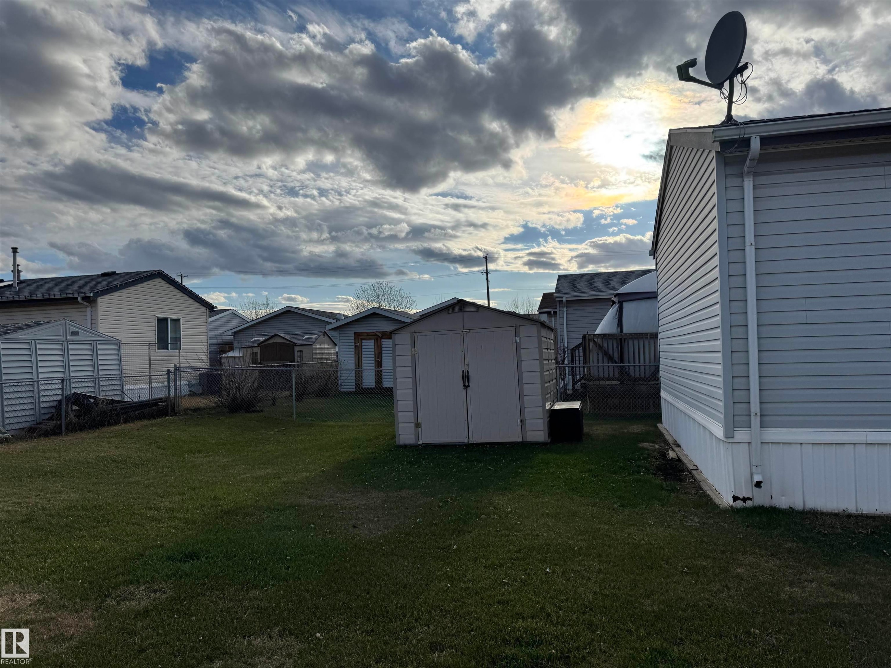 Expansive rear yard featuring green lawn, a metal storage shed, and a privacy fence - 1637 68 Avenue, Edmonton, AB - Outdoor