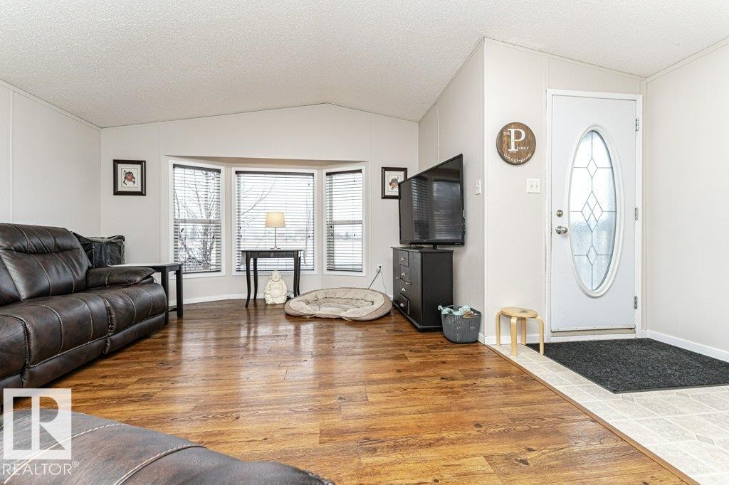 Living area featuring wood-finish flooring, a bay window with blinds, and a vaulted ceiling - 1637 68 Avenue, Edmonton, AB - Indoor Photo Showing Living Room