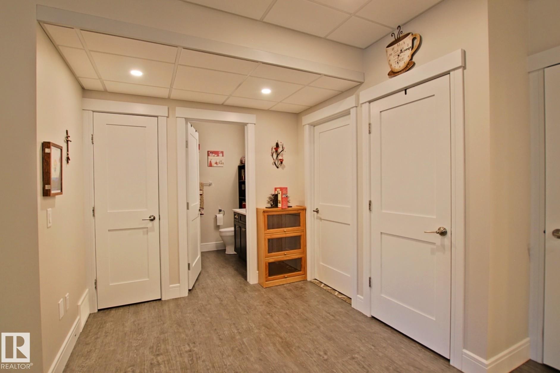 Interior hallway with wood-finish flooring, white paneled doors, recessed lighting, and a drop ceiling - 9711 223 Street, Edmonton, AB
