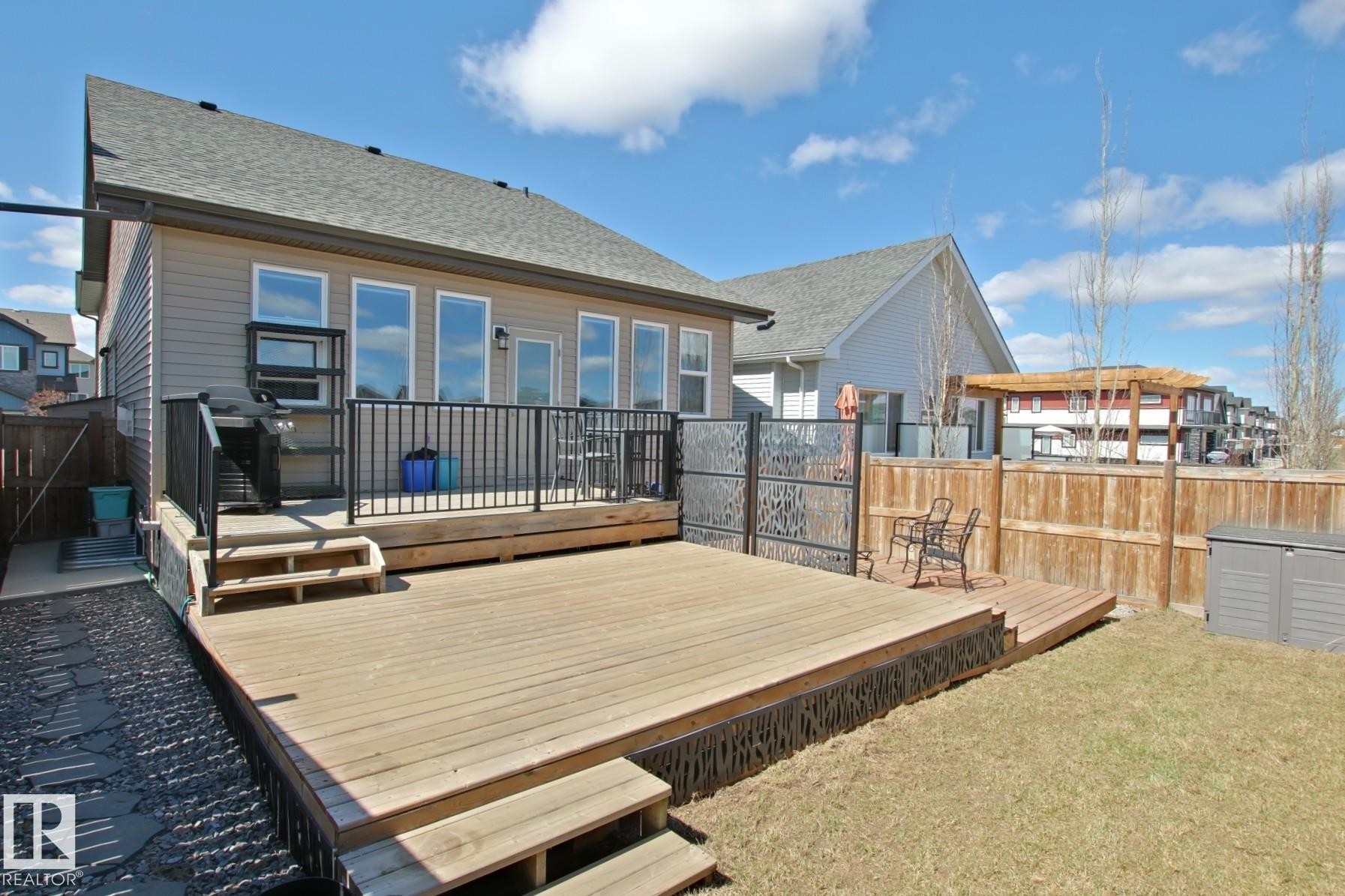 Expansive wood deck featuring black metal railings and direct access to the interior - 9711 223 Street, Edmonton, AB