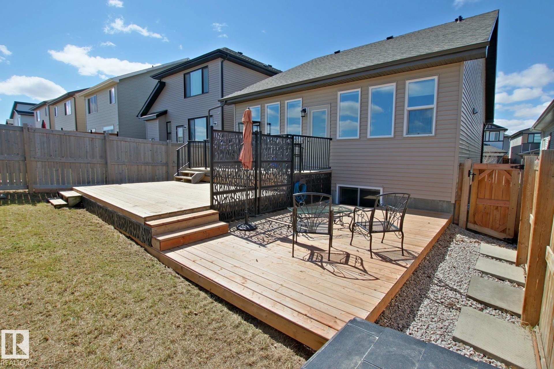 Expansive multi-level wood-finish deck with integrated steps, surrounded by a manicured lawn and a privacy fence - 9711 223 Street, Edmonton, AB