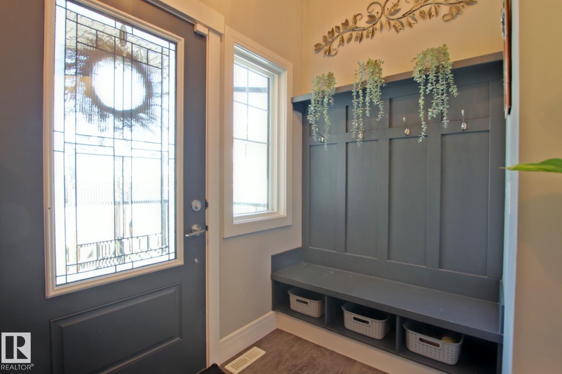 Entryway featuring a dark gray door with leaded glass, a sidelight window, and wood-finish flooring - 9711 223 Street, Edmonton, AB