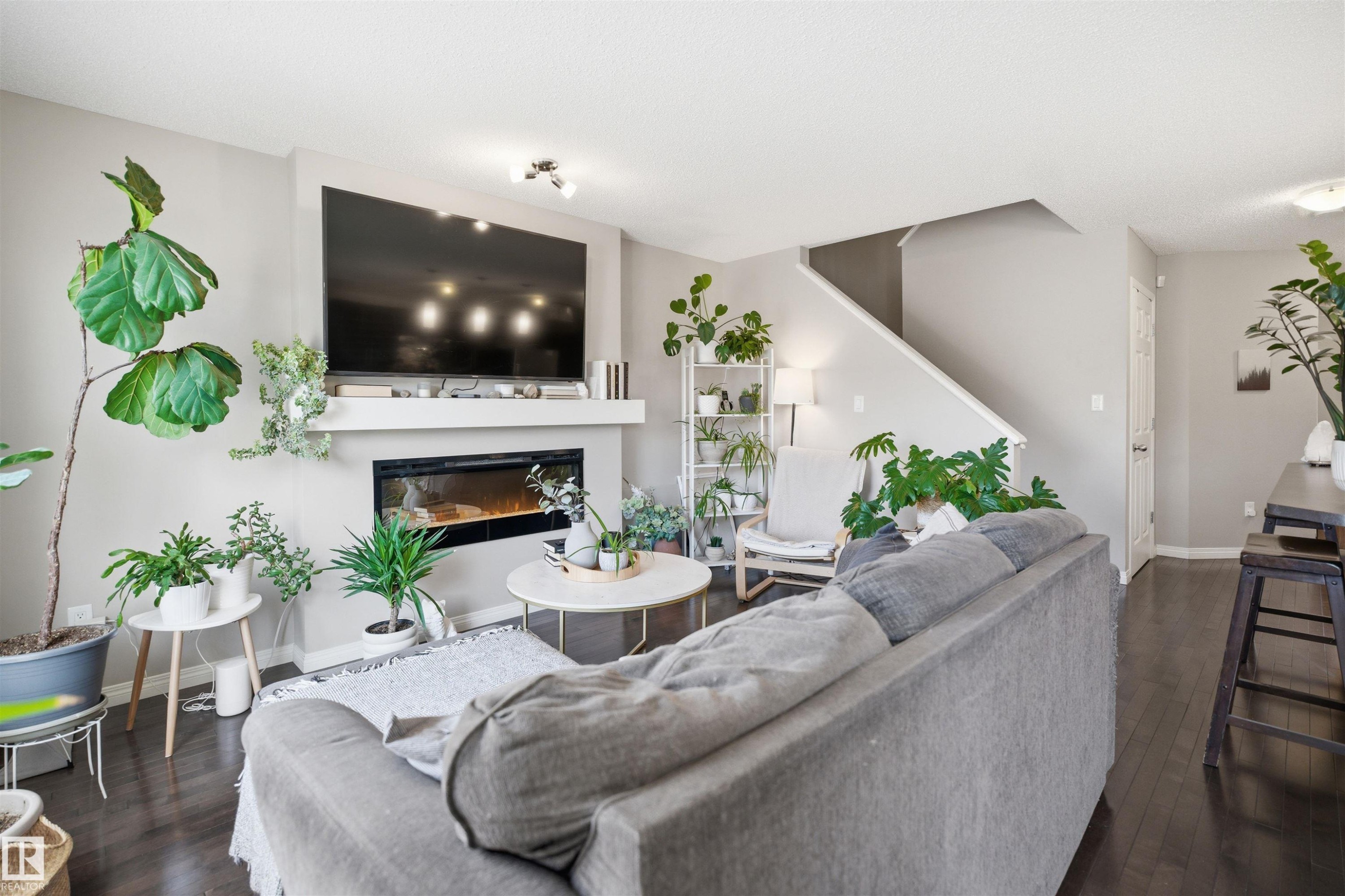 Living area featuring dark wood-finish flooring, light grey walls, and a contemporary fireplace with a white mantel - 7323 24 Ave, Edmonton, AB - Indoor Photo Showing Bedroom