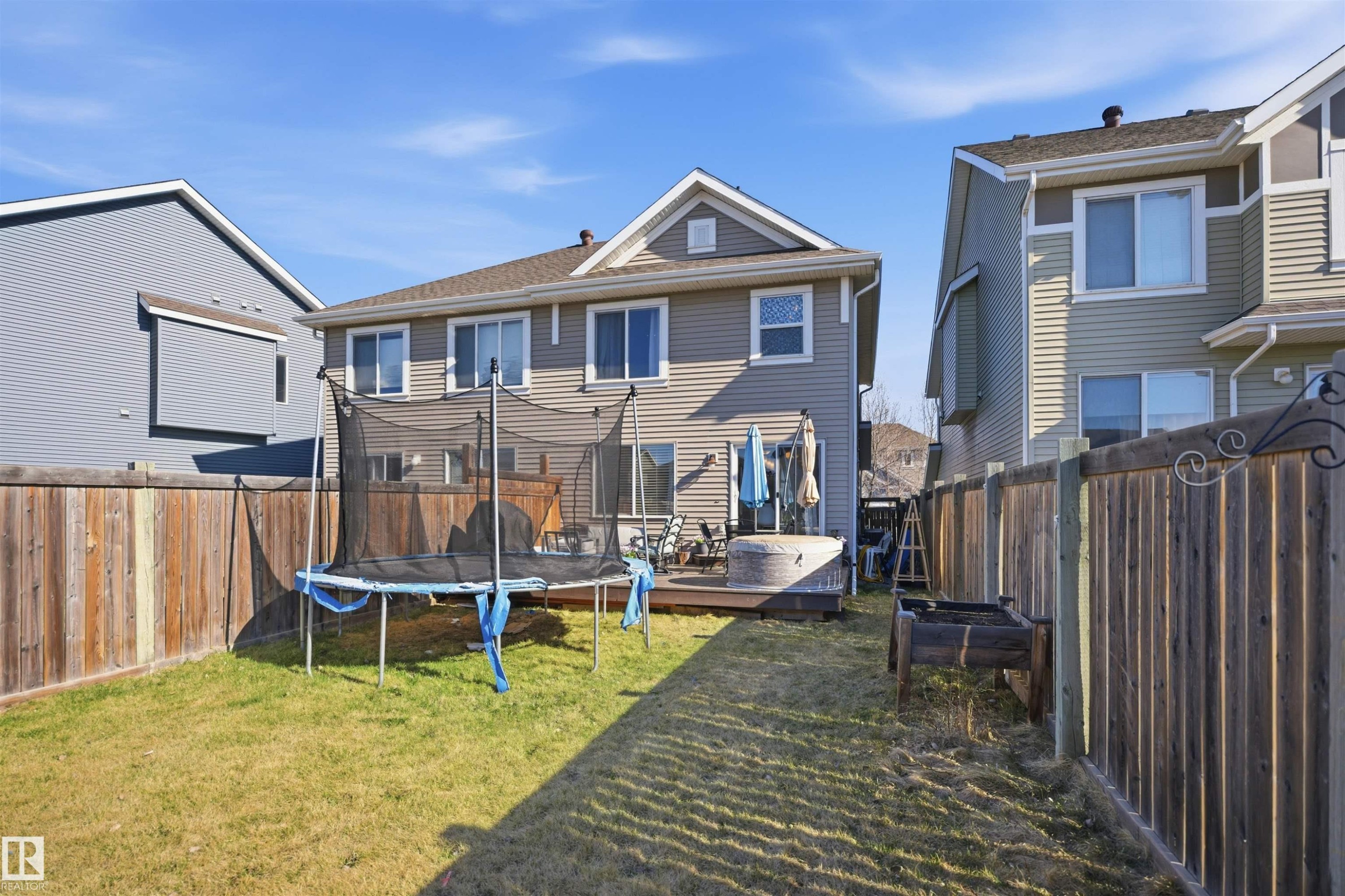 Expansive backyard featuring a manicured lawn, a wood deck, a built-in hot tub, and a privacy fence - 7323 24 Ave, Edmonton, AB - Outdoor