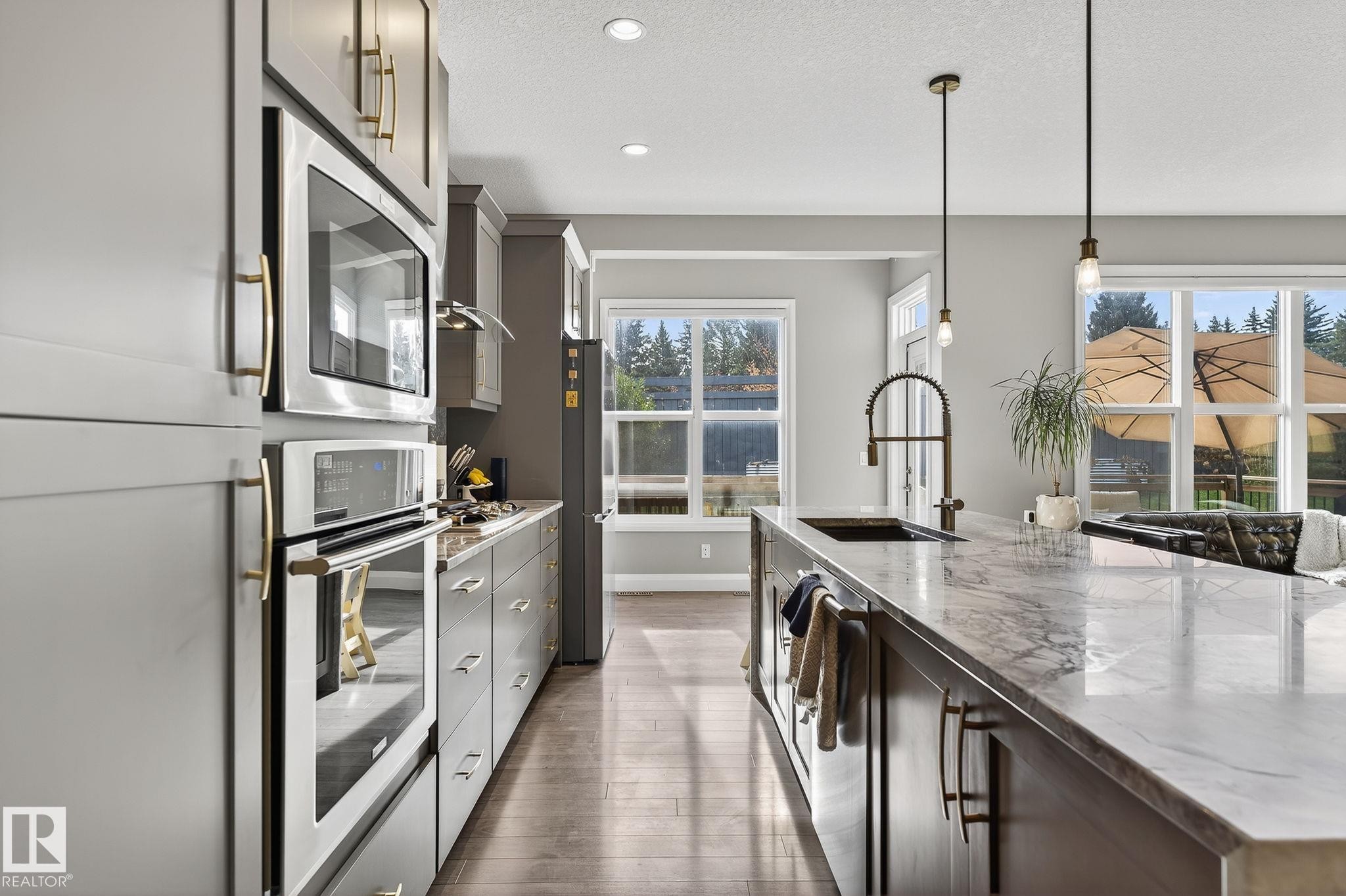 Modern kitchen featuring an expansive island with a waterfall edge countertop, built-in sink, and pendant lighting - 1737 Dumont Crescent, Edmonton, AB - Indoor Photo Showing Kitchen