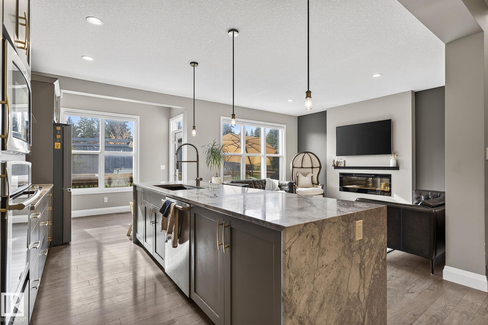 Open-concept kitchen and living area featuring a large island with a waterfall countertop, integrated sink, and pendant lighting - 1737 Dumont Crescent, Edmonton, AB - Indoor Photo Showing Kitchen With Upgraded Kitchen
