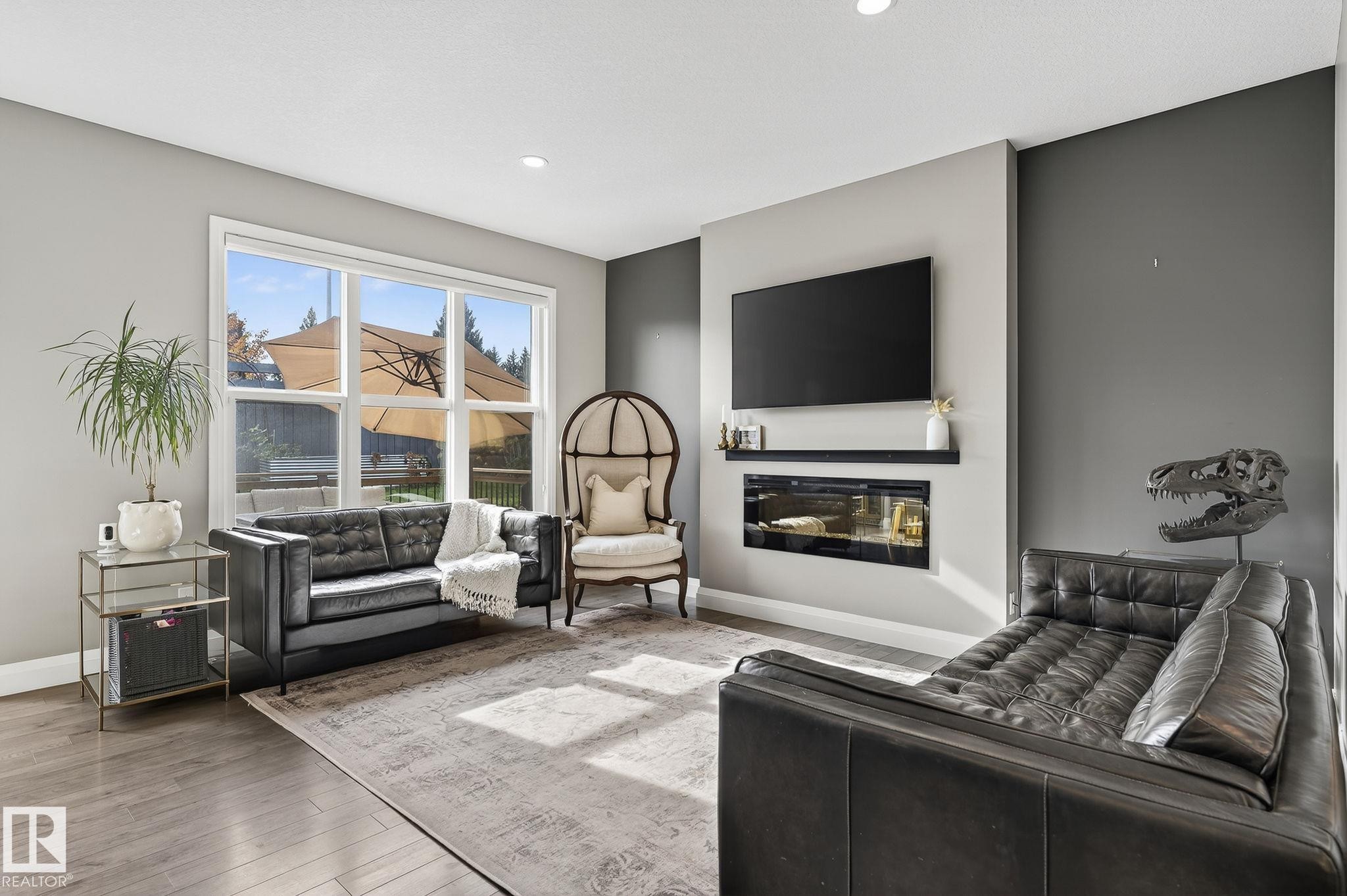 Living space featuring wood-finish flooring and a large window overlooking the outdoor area - 1737 Dumont Crescent, Edmonton, AB - Indoor Photo Showing Living Room With Fireplace