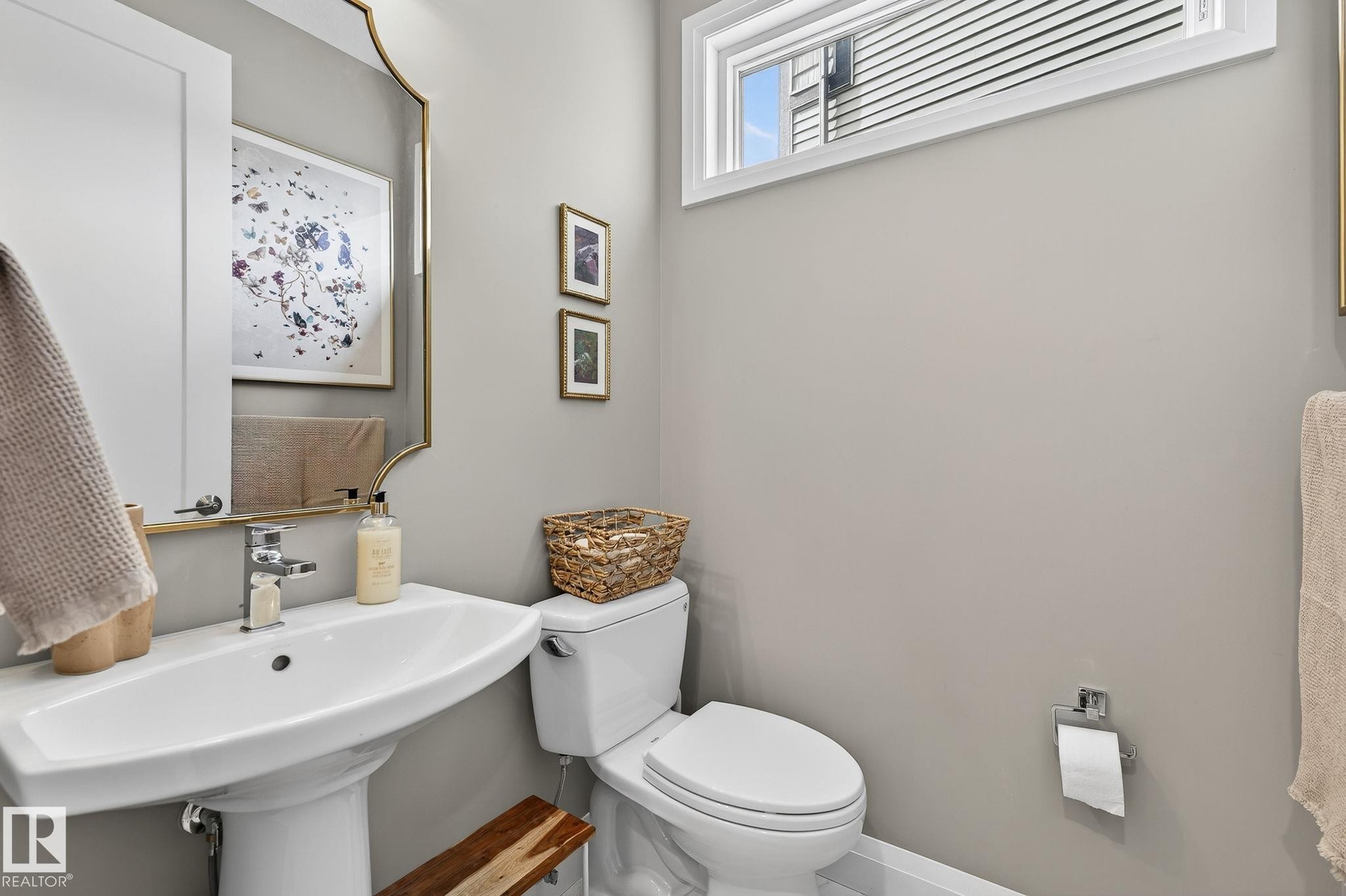 Pedestal sink with polished chrome faucet, rectangular wall mirror with gold-finish frame, and modern white toilet - 1737 Dumont Crescent, Edmonton, AB - Indoor Photo Showing Bathroom