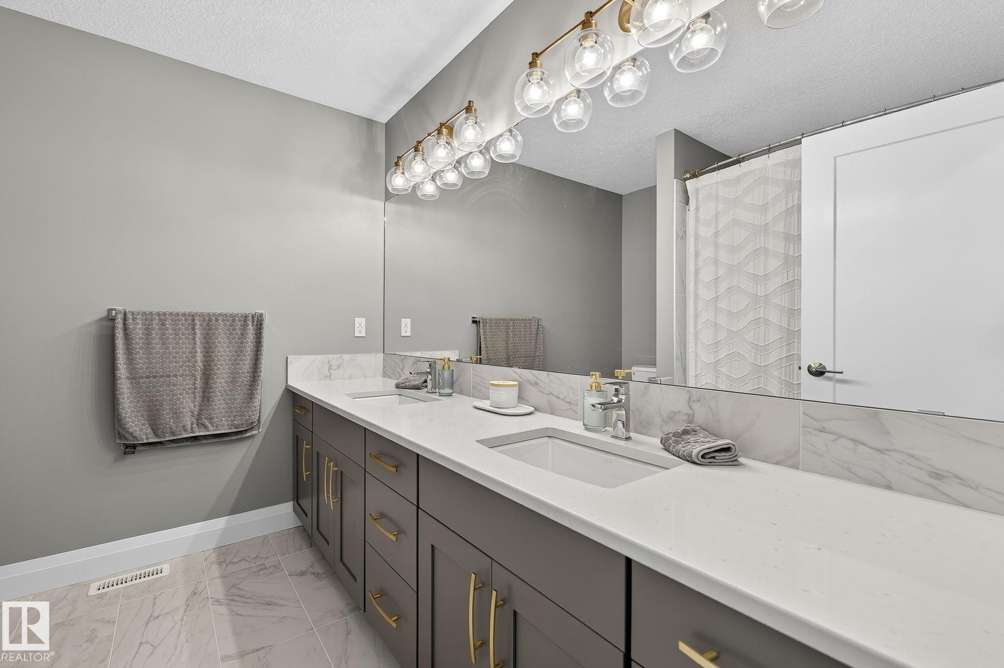 Double vanity featuring integrated sinks, light-toned countertops, and dark cabinetry with gold-tone hardware - 1737 Dumont Crescent, Edmonton, AB - Indoor Photo Showing Bathroom