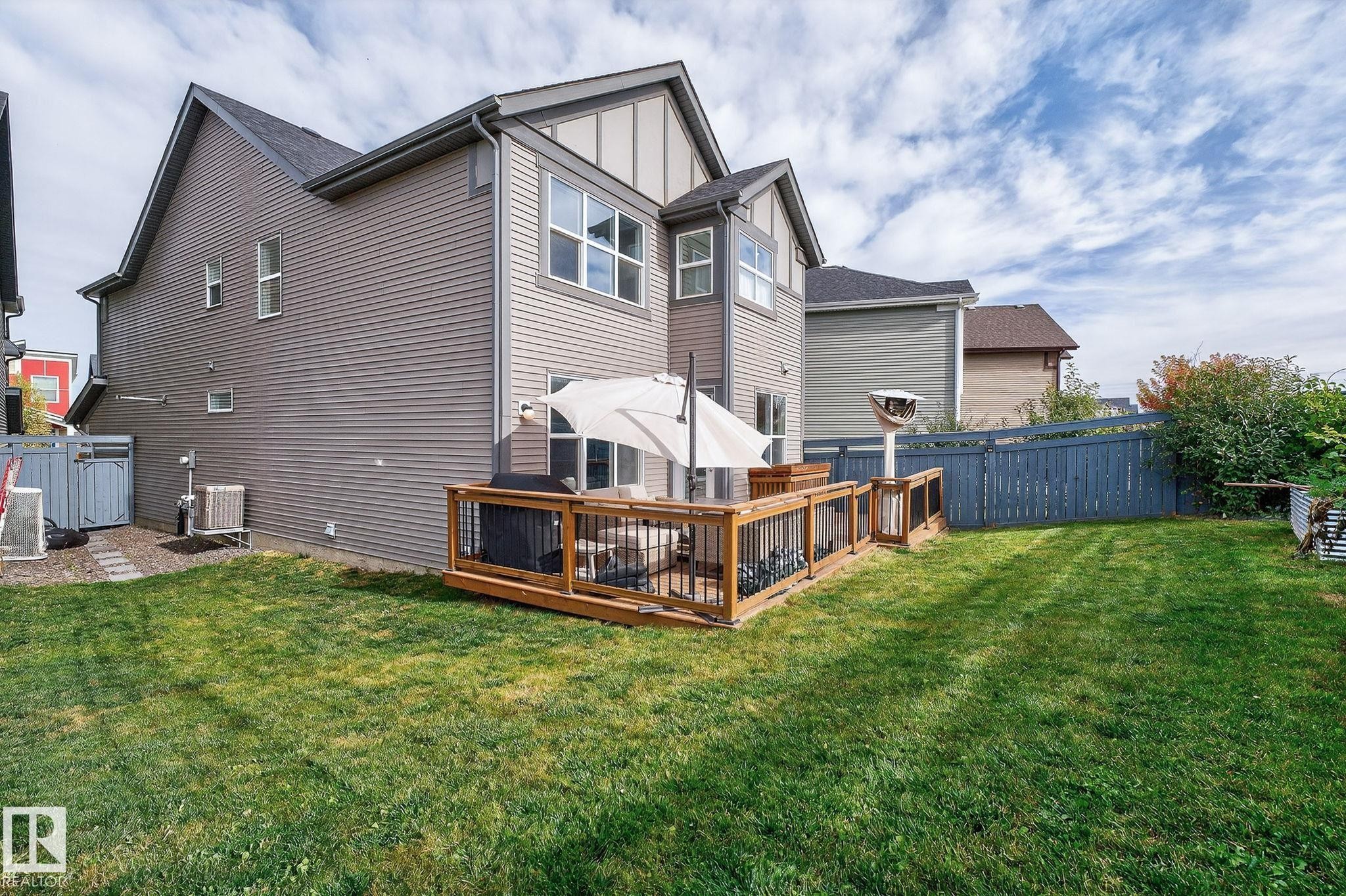 Expansive backyard featuring a manicured lawn, a wooden deck with black metal railings, and a privacy fence - 1737 Dumont Crescent, Edmonton, AB - Outdoor With Deck Patio Veranda With Exterior