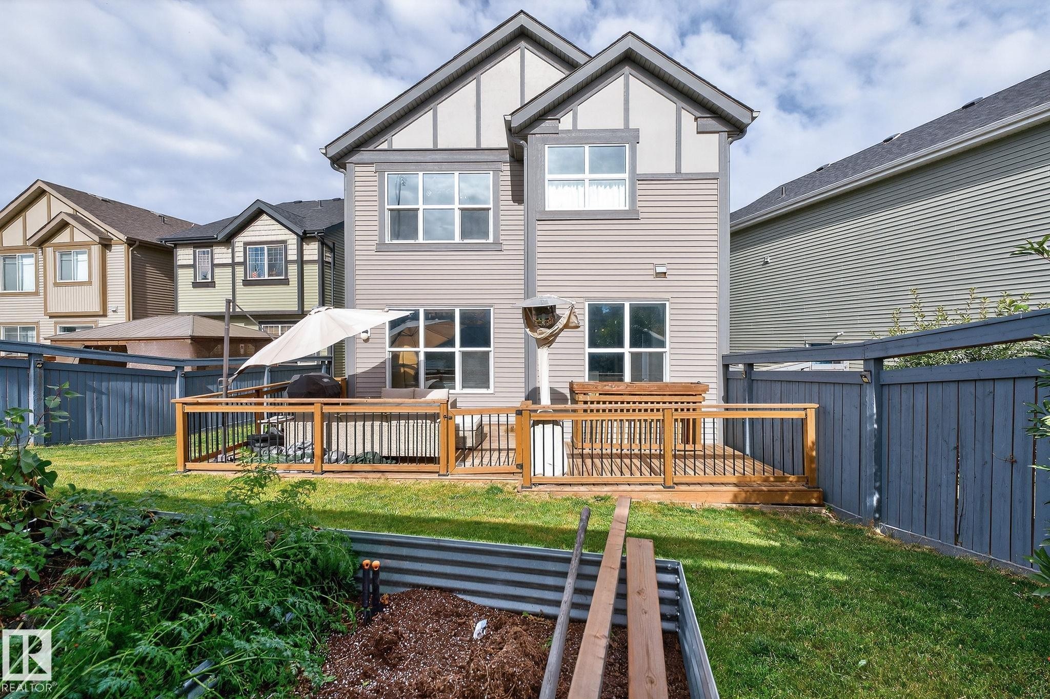 Backyard featuring a wooden deck with black metal balusters, a privacy fence, and a raised garden bed - 1737 Dumont Crescent, Edmonton, AB - Outdoor With Deck Patio Veranda