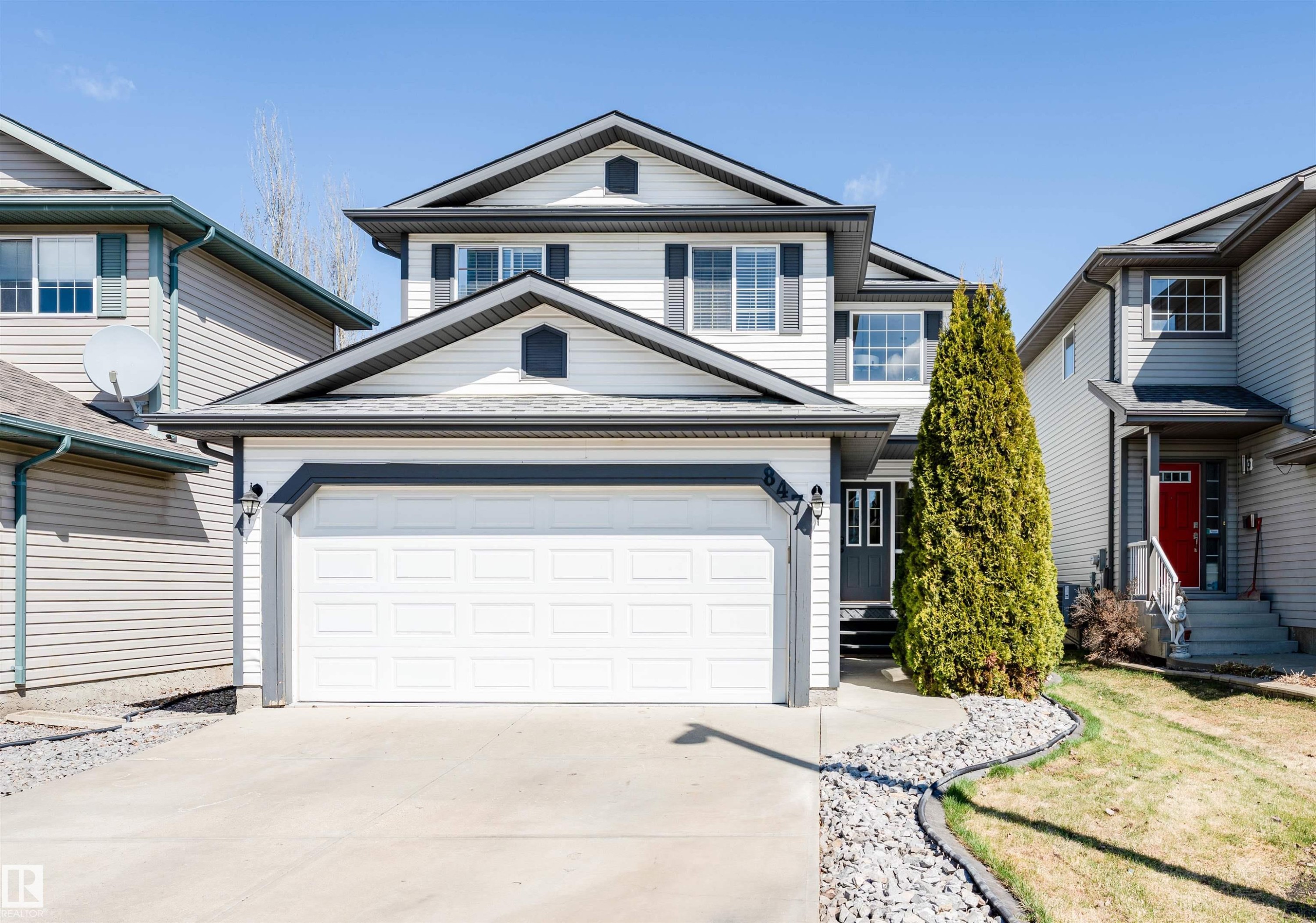 Contemporary two-story residence featuring white siding, a prominent two-car garage, and dark trim accents - 847 Blacklock Way, Edmonton, AB - Outdoor