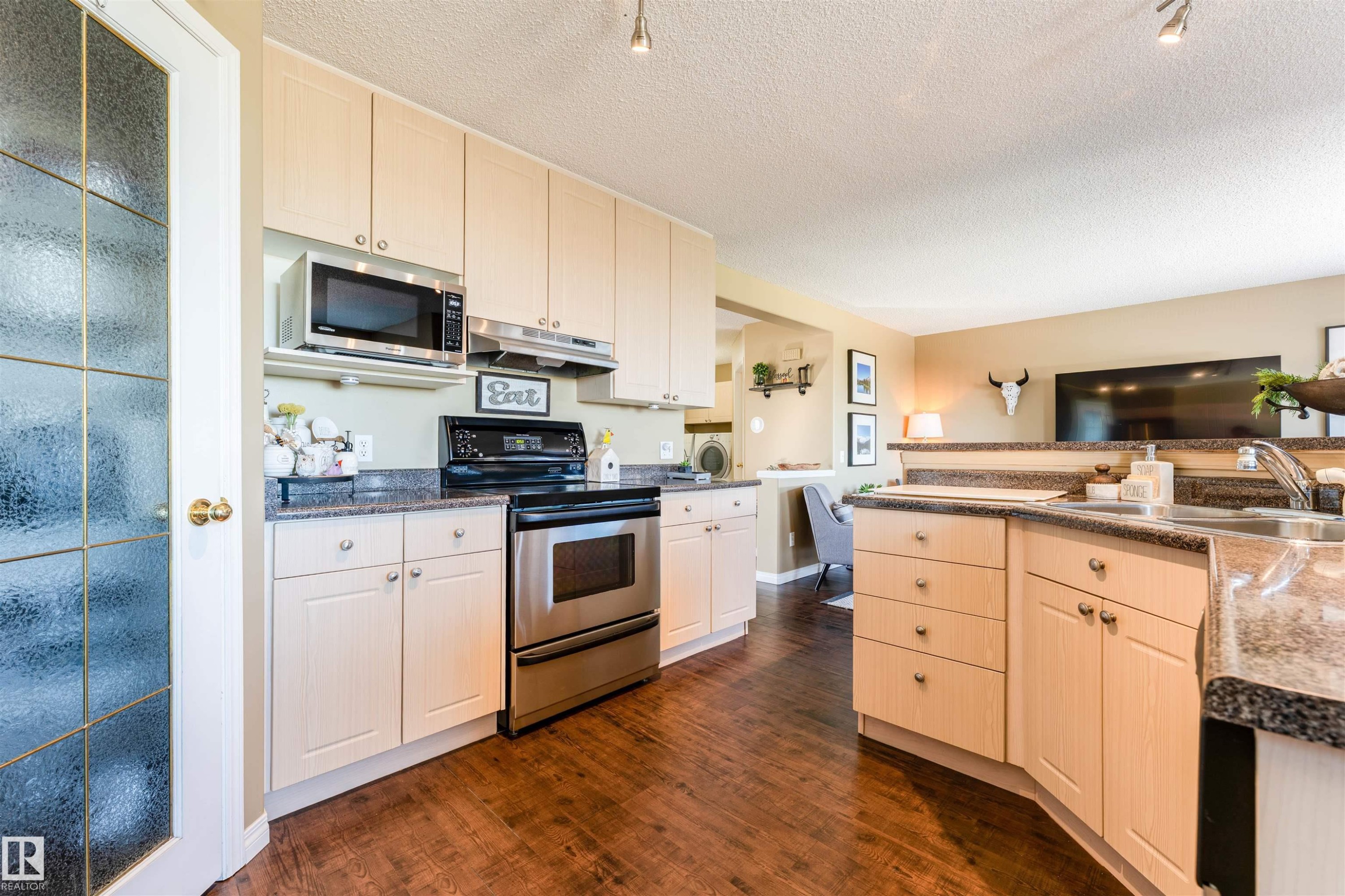 Kitchen featuring light-toned cabinetry, stainless steel appliances, dark flecked countertops, and dark wood-finish flooring - 847 Blacklock Way, Edmonton, AB - Indoor Photo Showing Kitchen