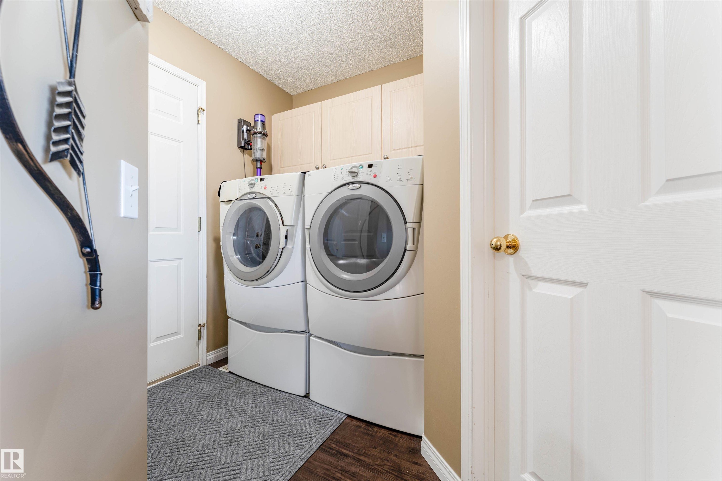 Laundry area featuring side-by-side washer and dryer, upper cabinetry, and wood-finish flooring - 847 Blacklock Way, Edmonton, AB - Indoor Photo Showing Laundry Room