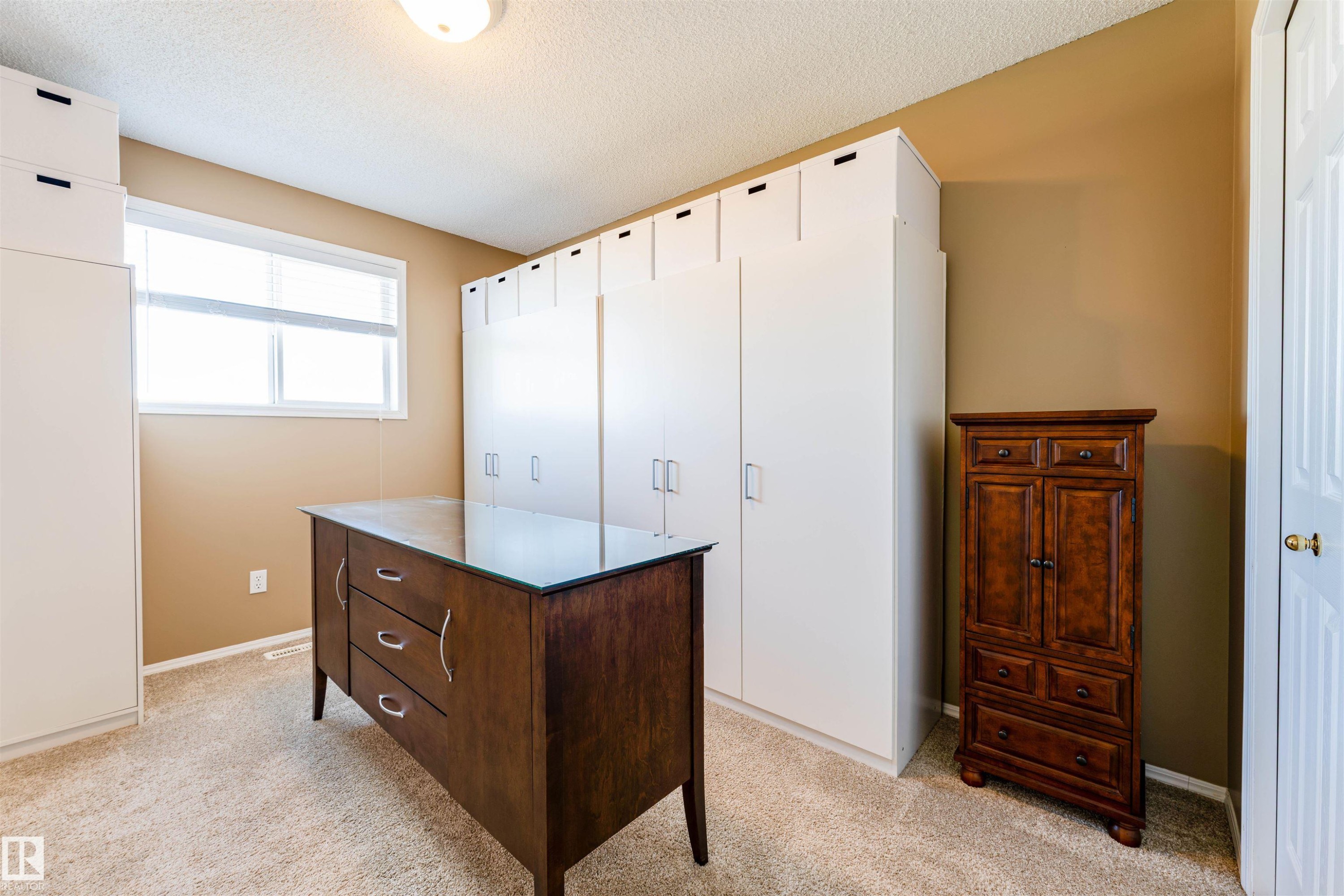 Dedicated room featuring extensive built-in cabinetry, a double-pane window with horizontal blinds, and textured ceiling finish - 847 Blacklock Way, Edmonton, AB - Indoor