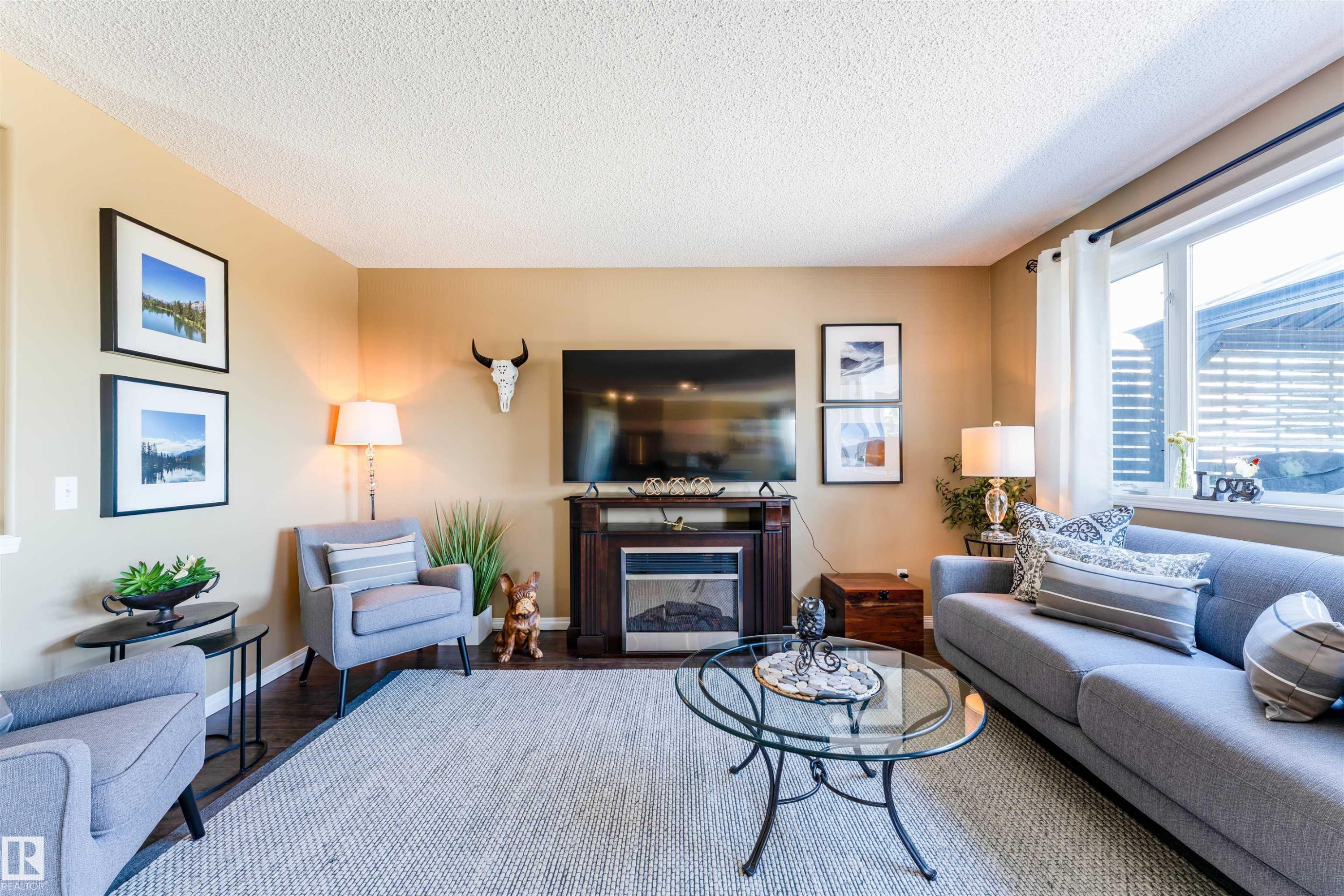 Living area featuring a floor-to-ceiling window, dark wood-finish flooring, and a built-in fireplace with a dark wood surround - 847 Blacklock Way, Edmonton, AB - Indoor Photo Showing Living Room With Fireplace