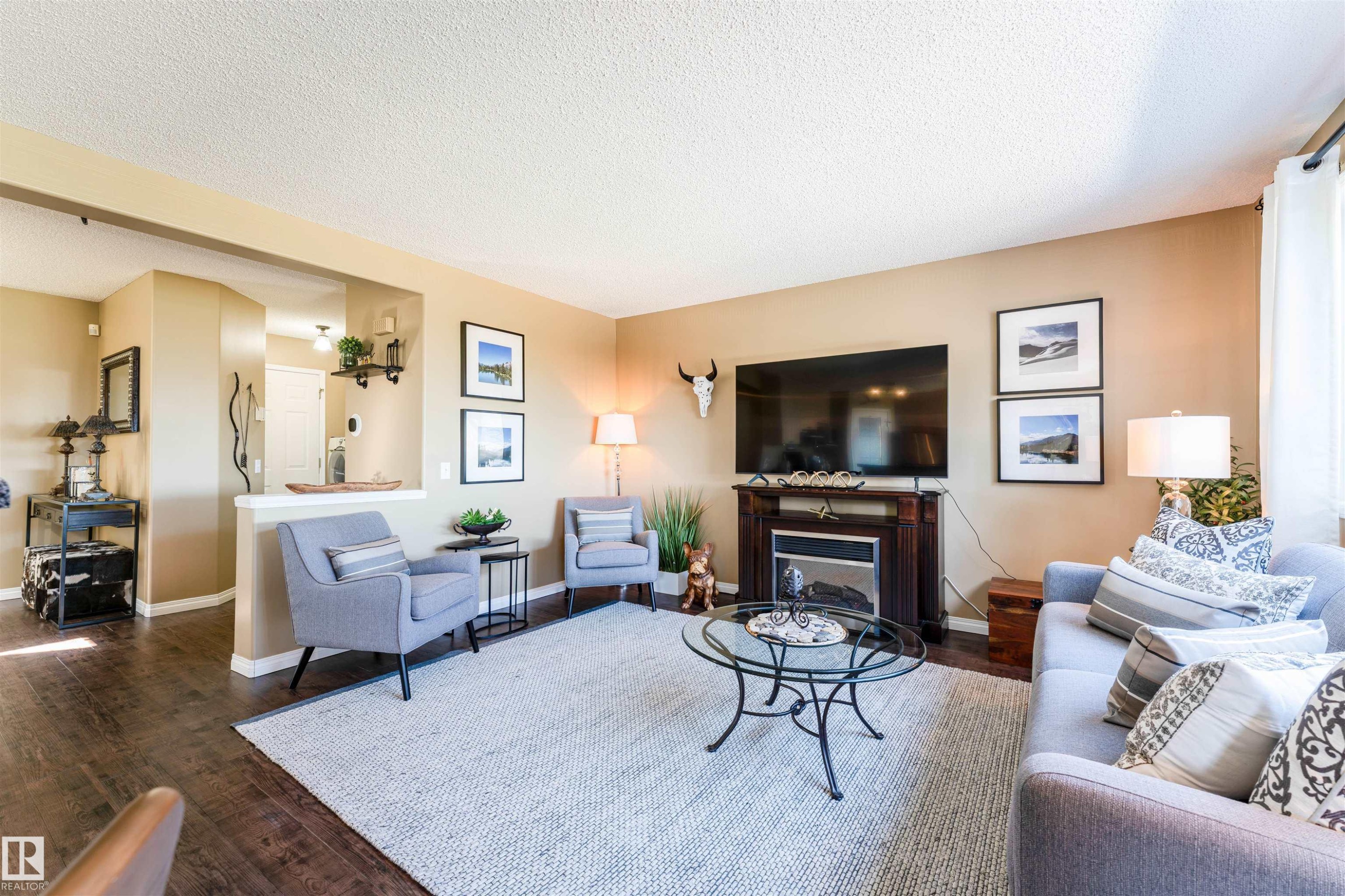Living area featuring wood-finish flooring, a built-in fireplace with a dark wood mantel, and an open pass-through archway - 847 Blacklock Way, Edmonton, AB - Indoor Photo Showing Living Room